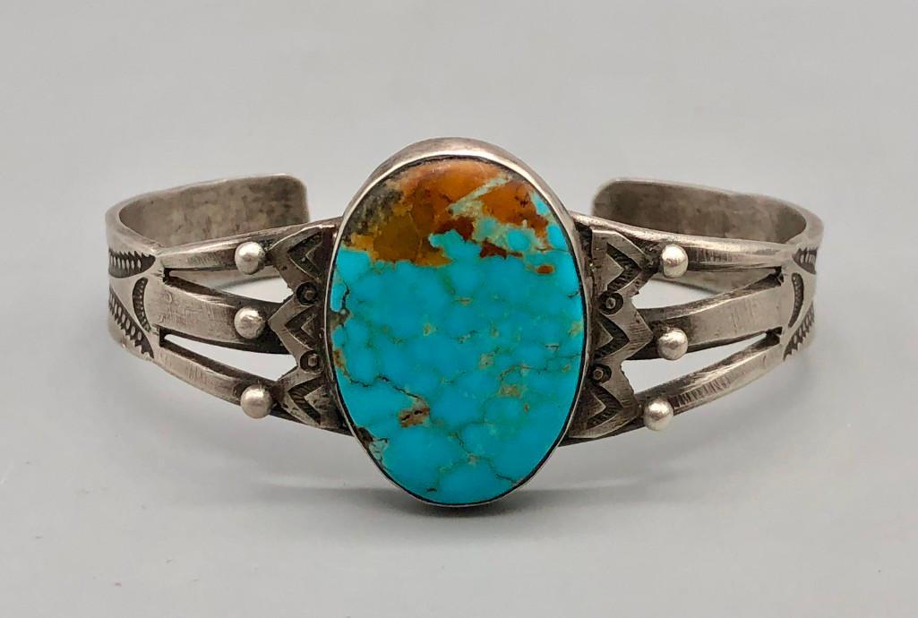 1930s-1940s Era Turquoise and Sterling Silver Bracelet: Available in this lot is a 1930s-1940s era turquoise and sterling silver bracelet. This stunning piece has a beautiful bluish turquoise cabochon in the center, with silver dots and hand stamped design