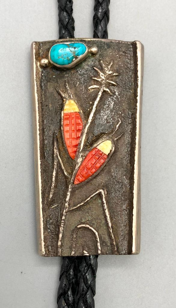 Corn and Moon Tufa Cast Bolo- John Hornbeck: Offered in this lot is a coral and moon tufa cast bolo tie by John Hornbeck. This stunning slide has coral and shell ear of corn themed cabochons with eye catching silverwork and a turquoise cabochon 