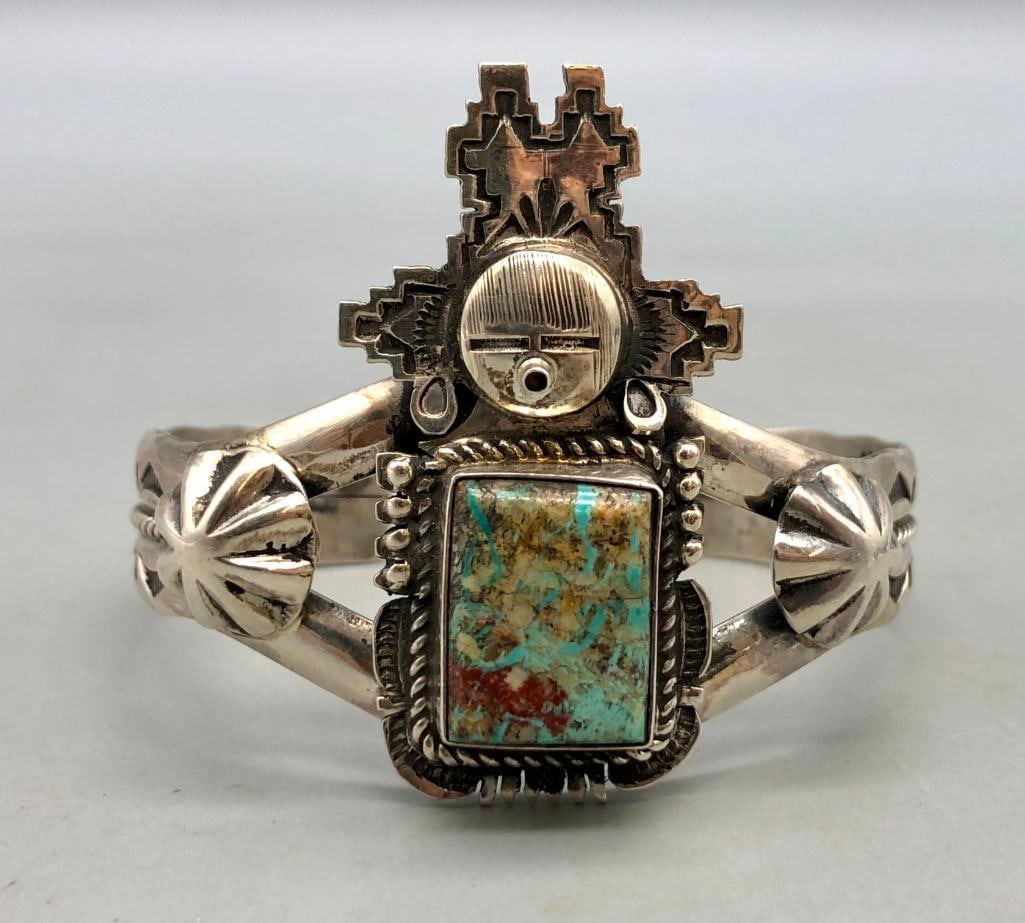Kachina Themed Turquoise Bracelet By Bennie Ration: For your bidding enjoyment we present a Kachina themed turquoise bracelet by Bennie Ration. This bracelet features a central turquoise cabochon resting in a smooth silver bezel surrounded by twisted w