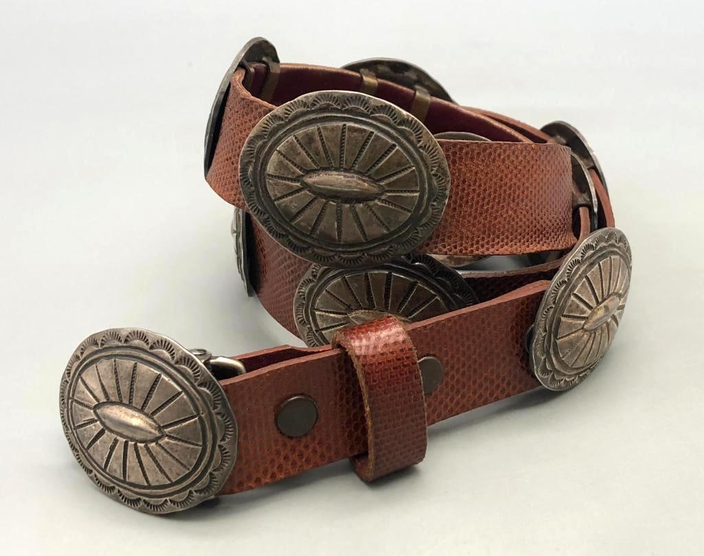 Vintage Sterling Silver Conchos On A Tom Taylor Belt: In this lot, we bring you sterling silver conchos on a Tom Taylor belt. This vintage belt has 11 outstanding oval conchos, each with hand stamped designs and filework in a sun burst pattern. The conch