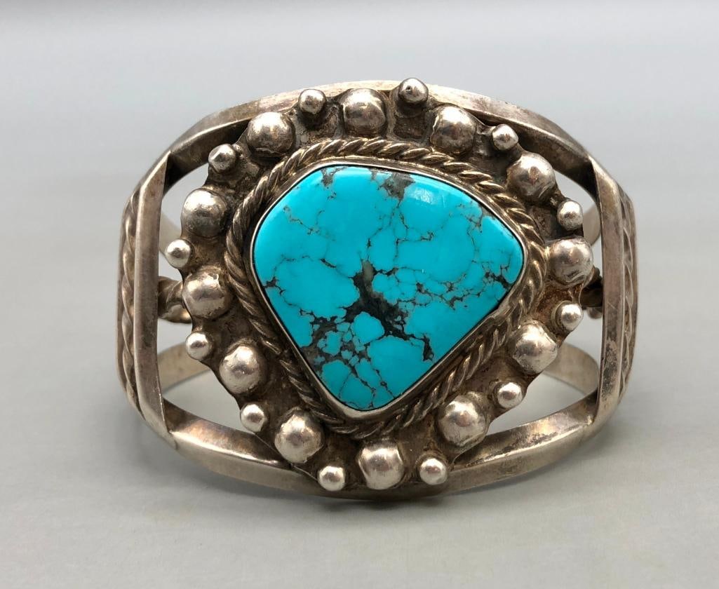 Vintage Turquoise And Sterling Silver Bracelet: For your bidding enjoyment we present a vintage turquoise and sterling silver bracelet. This bracelet features a lovely central turquoise cabochon resting in a smooth silver bezel surrounded by twiste