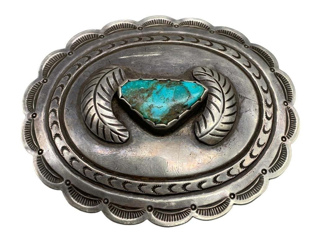 Vintage Turquoise And Sterling Silver Belt Buckle: Available here in this lot is a vintage turquoise and sterling silver belt buckle. This sterling silver belt buckle features a central turquoise cabochon resting in a scalloped bezel accented with han