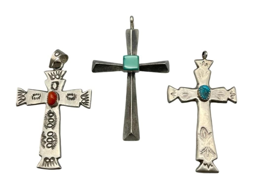 Three Cross Pendants: Available here are three cross pendants. This lot features something for everyone. Each of these pendants showcases a cross design highlighted with a cabochon of coral or turquoise resting in eit