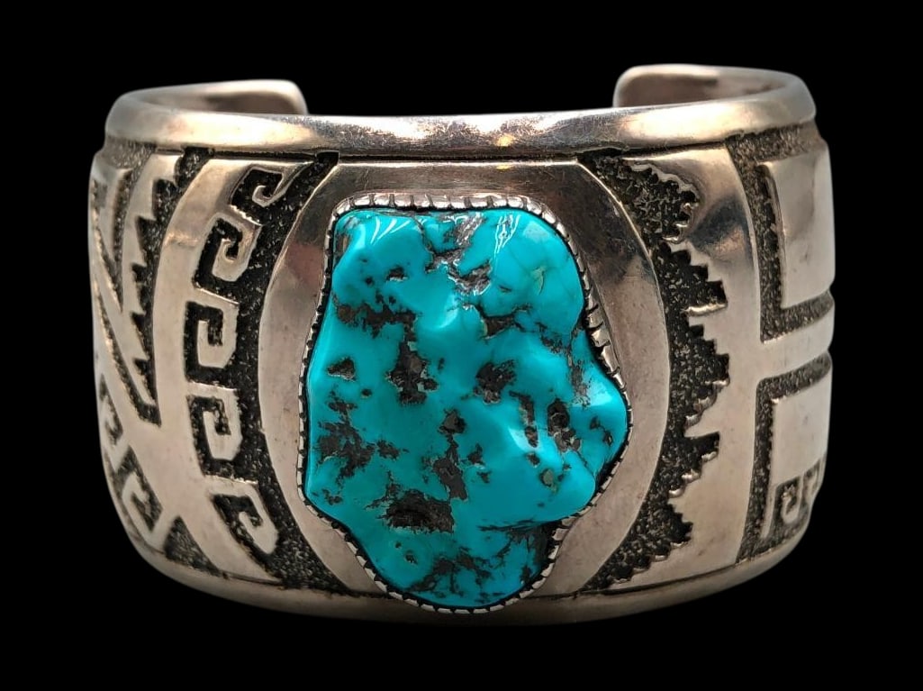 Turquoise And Overlay Design Bracelet: For your bidding pleasure is a turquoise and overlay design bracelet. This bracelet features a central nugget style turquoise cabochon resting in a smooth hand stamped silver bezel. The setting is dis