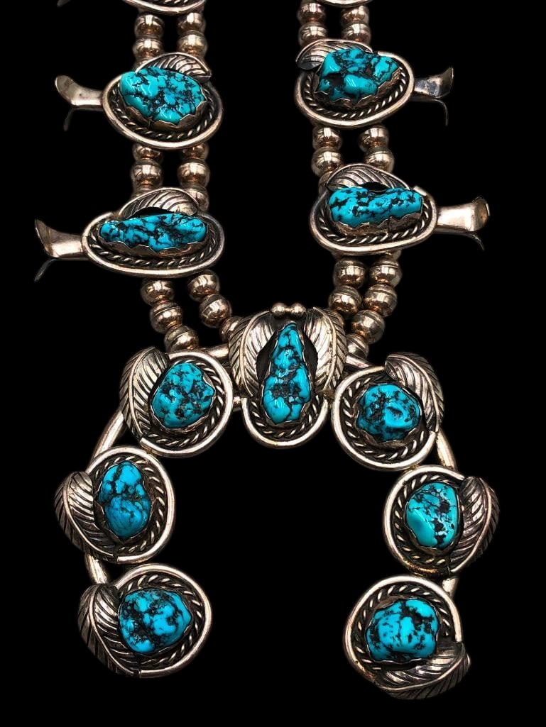 Vintage Turquoise And Sterling Silver Squash Blossom Necklace: Offered here for your consideration is a vintage turquoise and sterling silver squash blossom necklace. This necklace showcases a conjoined two wire naja highlighted with 10 nugget style turquoise cab