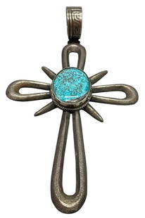 Tufa Cast Turquoise Cross Pendant: Offered here is a tufa cast turquoise cross pendant. This sterling silver cross pendant features a tufa cast design highlighted with a central turquoise cabochon resting in a smooth silver bezel surro