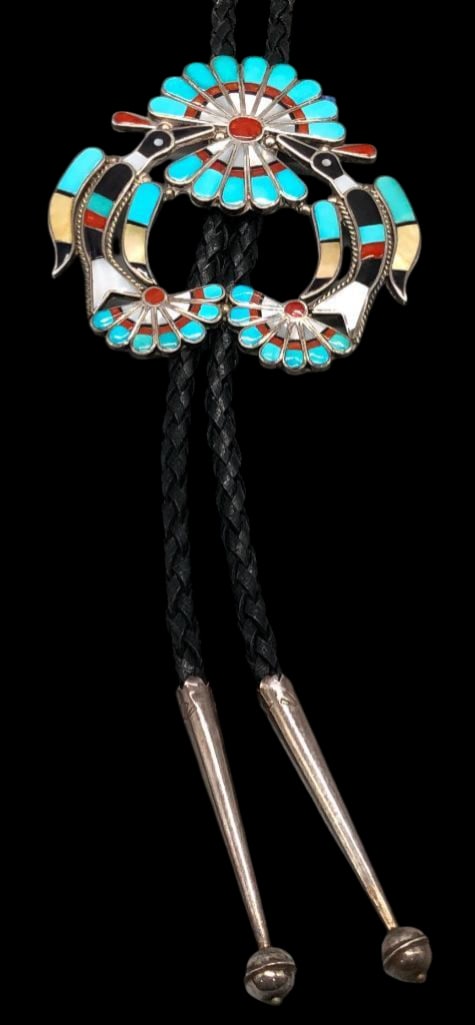 Zuni Inlay Bolo Tie By Linette Laiwakete: Offered in this lot is a Zuni inlay bolo tie by Linette Laiwakete. The slide features an intricate bird design created with inlay of turquoise, coral, mother of pearl, shell and onyx accented with twi