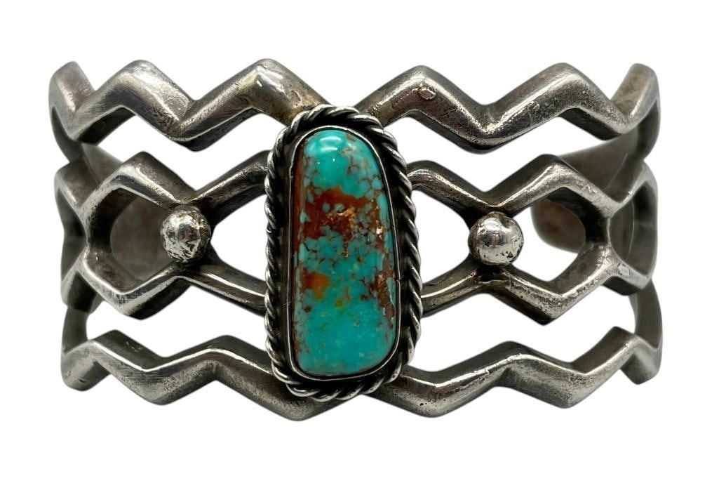 Turquoise & Sandcast Bracelet by F.L. Begay: For your bidding enjoyment we present a turquoise and sandcast bracelet by F.L. Begay. This bracelet features a lovely turquoise cabochon displayed in a smooth silver bezel. The central setting is sur