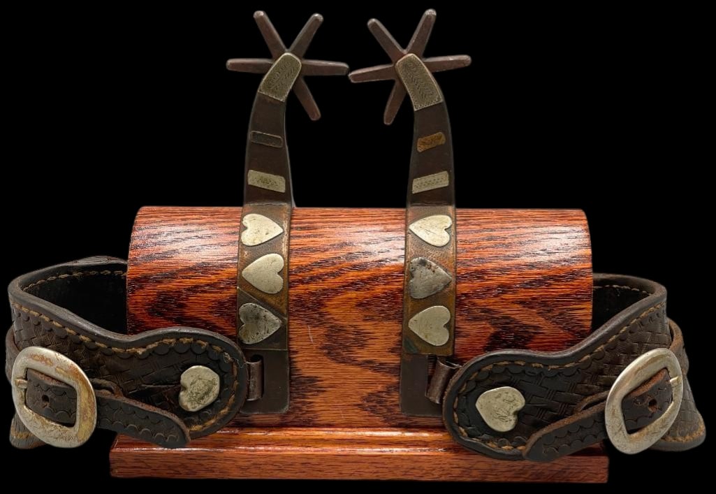 Kelly Brothers Heart Theme Spurs With Display Stand: Offered here for your consideration is a pair of Kelly Bros heart theme spurs with a display stand included. These spurs feature silver heart overlay designs along the heel bands with engraved silver