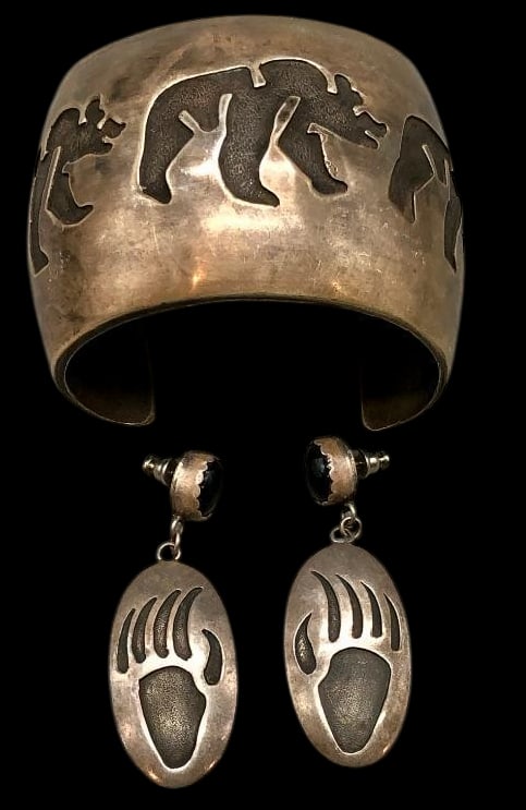 Sterling Silver, Bear And Bear Paw Theme Bracelet And Earrings: Offered here are a sterling silver bear, and bear paw theme bracelet and earrings. This cuff features a bear themed overlay design. The accompanying earrings feature onyx cabochon posts set in