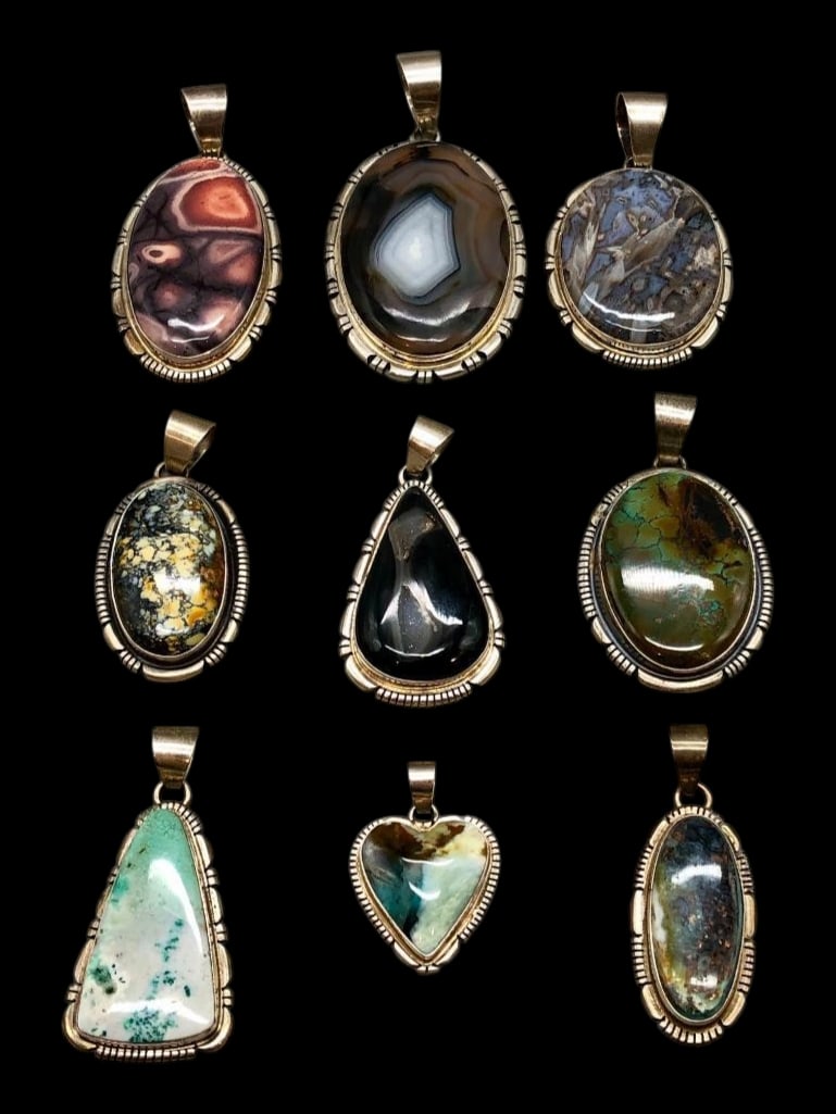 Nine Sterling Silver Pendants With Various Settings By Thomas Francisco: Available here in this lot are nine sterling silver pendants with various settings by Thomas Francisco. Each piece features a variety of stone cabochons in shades of black, green, purple and others ac