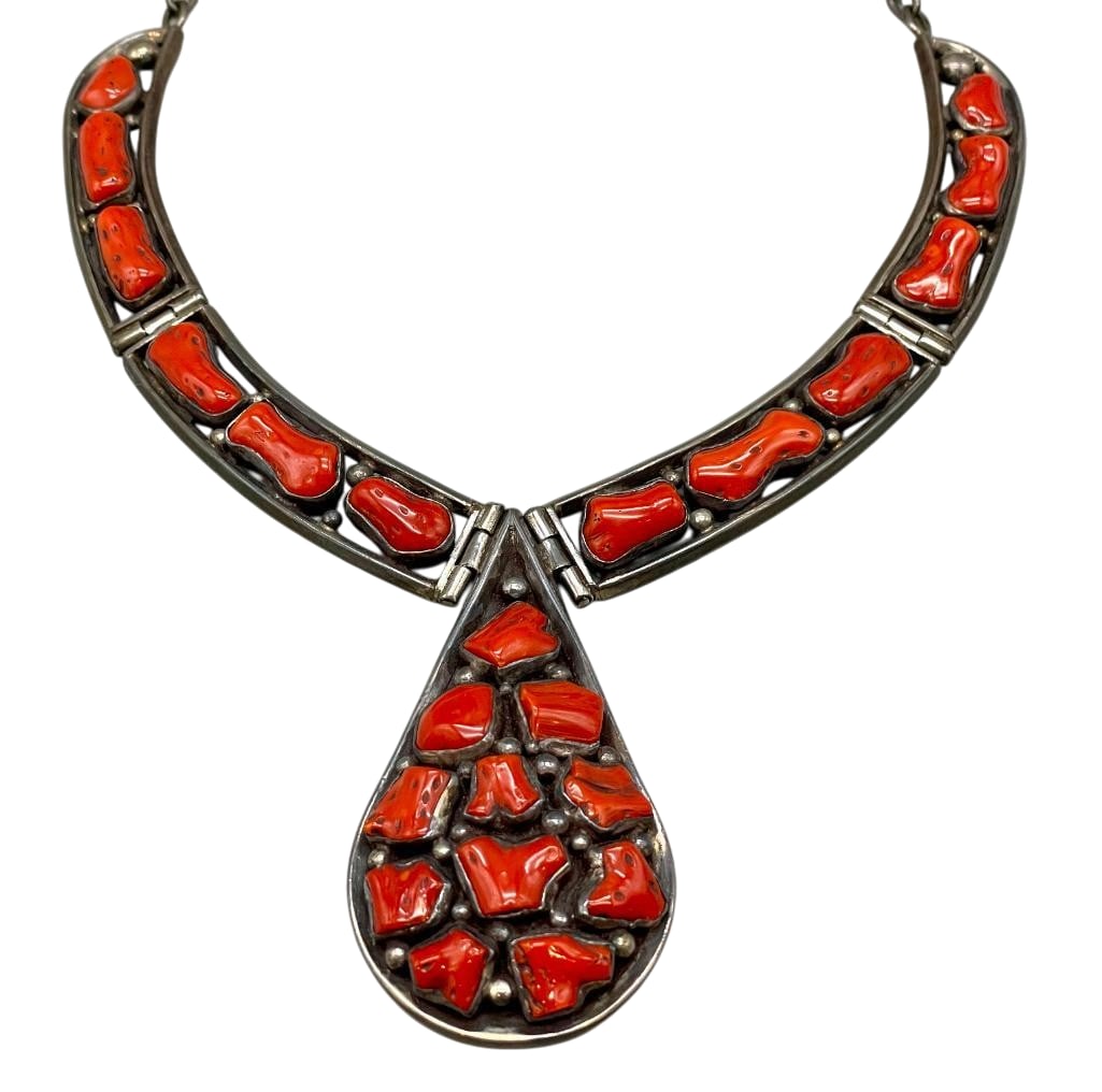 Vintage Coral And Sterling Silver Necklace: Offered here for your consideration is a vintage coral and sterling silver necklace. This piece features a central drop shaped pendant highlighted with coral cabochons set in smooth silver bezels. Acc