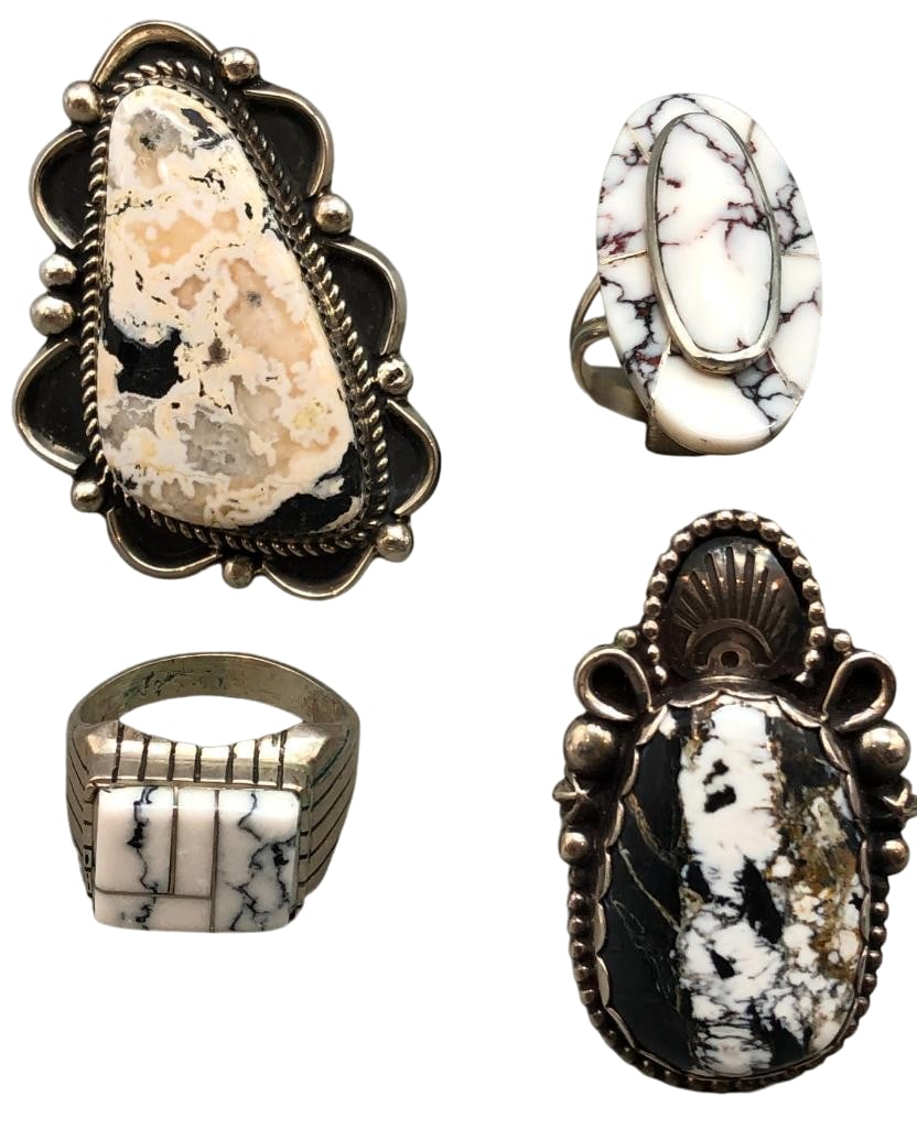 Four Sterling Silver And White Buffalo Rings: Offered here are four sterling silver and White Buffalo rings. Three of the pieces feature larger White Buffalo cabochons set in silver bezels and are accented by silver dots, arcs, darkened backgroun