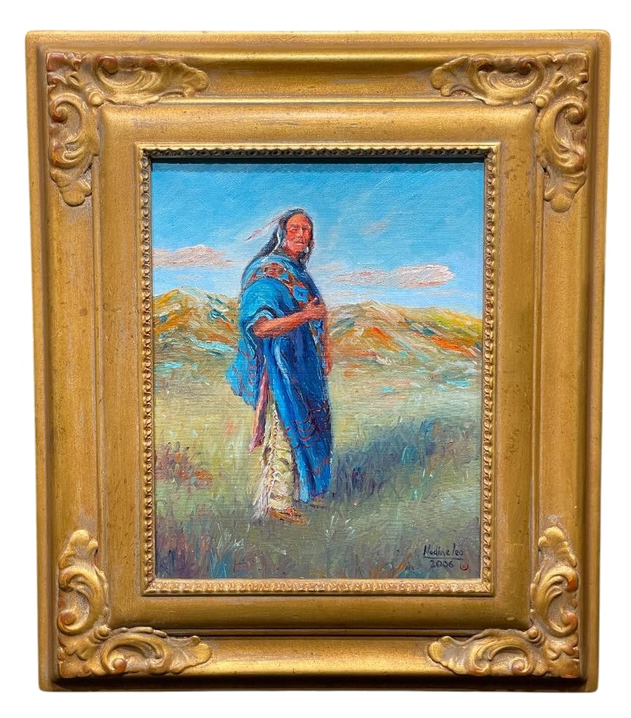 Original Native American Themed Oil Painting by Nadine Leo: Offered here for your consideration is an original oil painting by Nadine Leo depicting a Native American figure standing in an open landscape wearing a blue blanket. It is displayed in a gilt wooden 