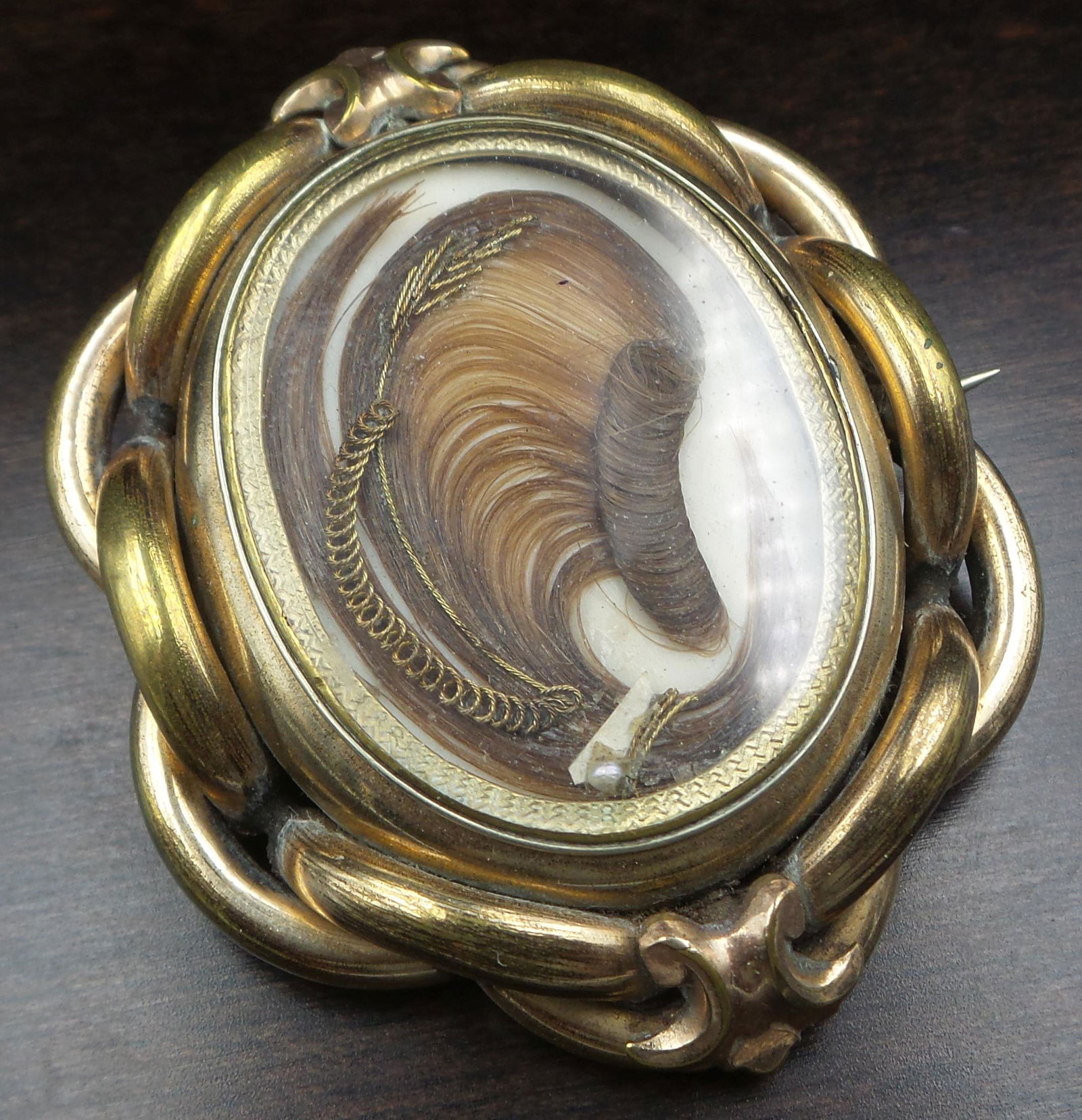 Mysterious Antique Victorian 10K Goldfilled Metal & French Hair Art Mourning Jewelry Brooch: A large antique mourning/sentimental locket front brooch. Crafted in 10K gold filled metal. The brooch features a front and back glass compartment and ornate gold tube work. The center of the brooch h