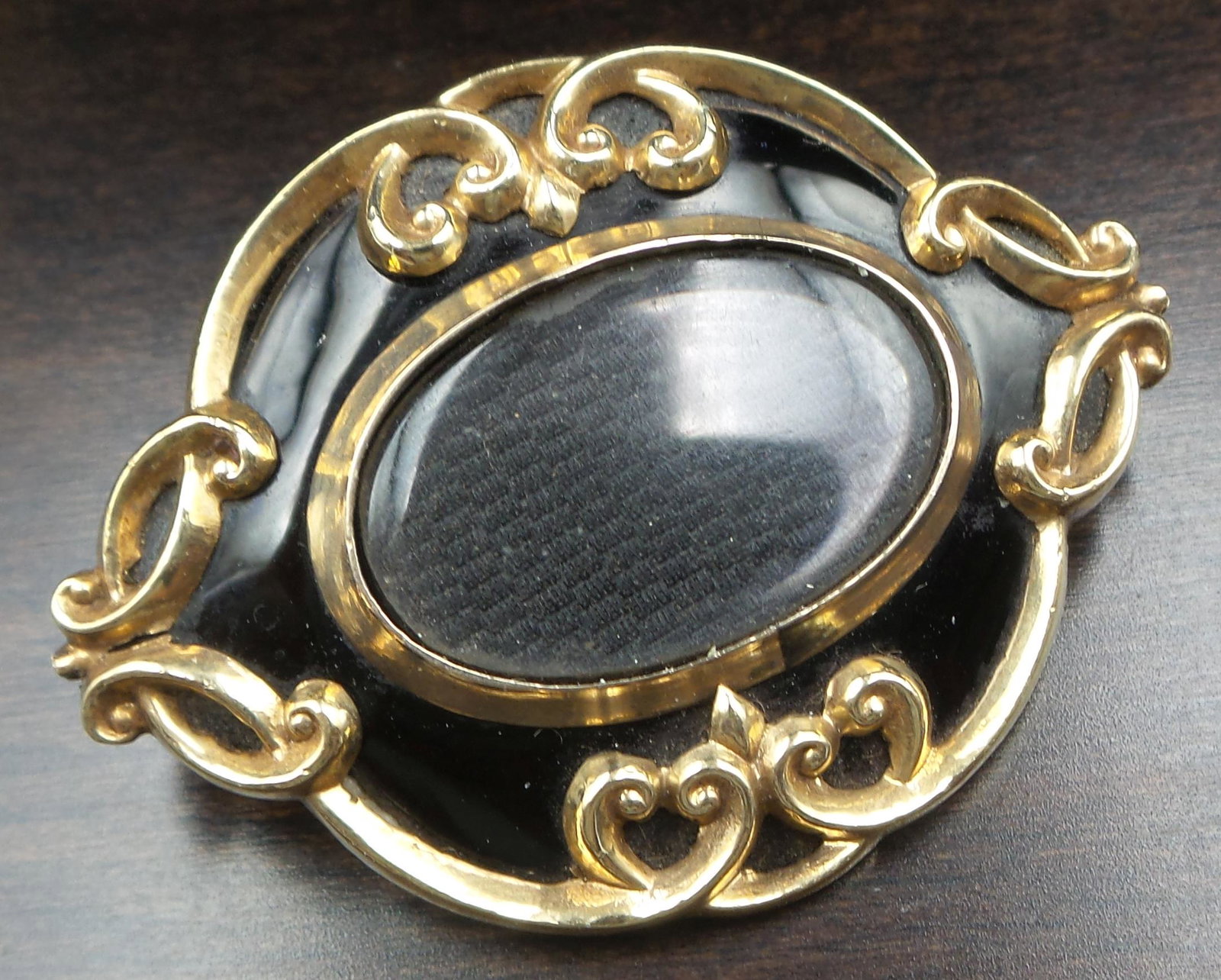 Large Antique Victorian 14K Gold, Black Enamel & French Hair Art Mourning Jewelry Brooch: A large antique mourning/sentimental locket front brooch. Crafted in solid 14K gold. The brooch features a glass compartment and ornate gold repousse work against a jet black enamel background. The ce