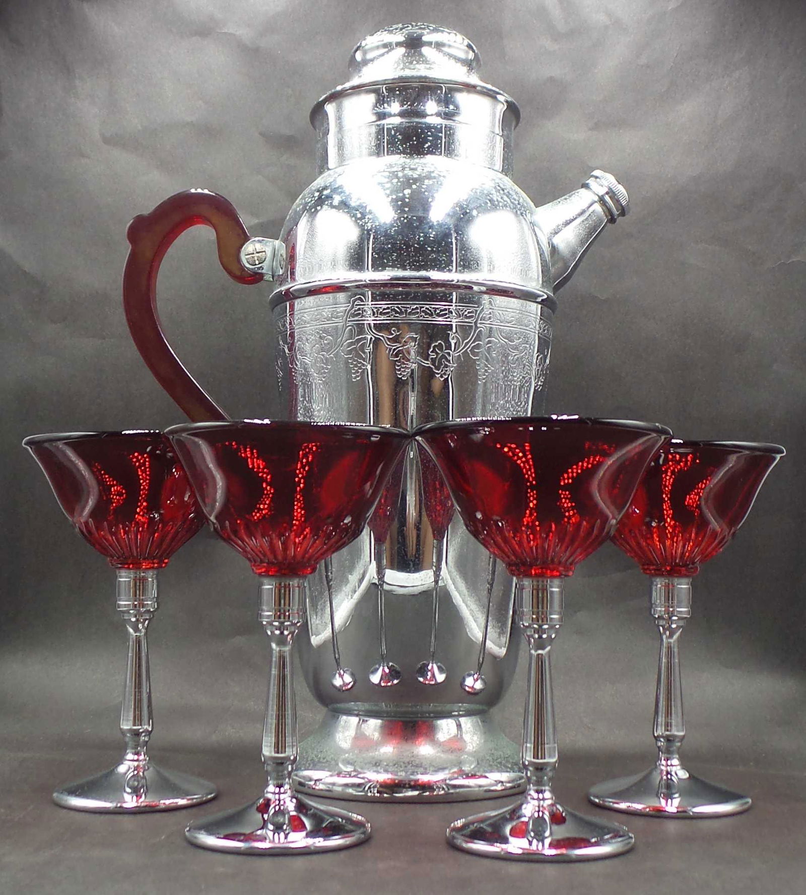 Vintage ca. 1930s Art Deco Cocktail Shaker /w Bakelite Handle & 4 Red Glasses: The shaker measures approx. 11 1/2" high x 7 1/2" wide (spigot to handle) x 4 1/4" in diameter (at the base). The set is in very good vintage condition, no chips, cracks, or repairs. The chrome platin
