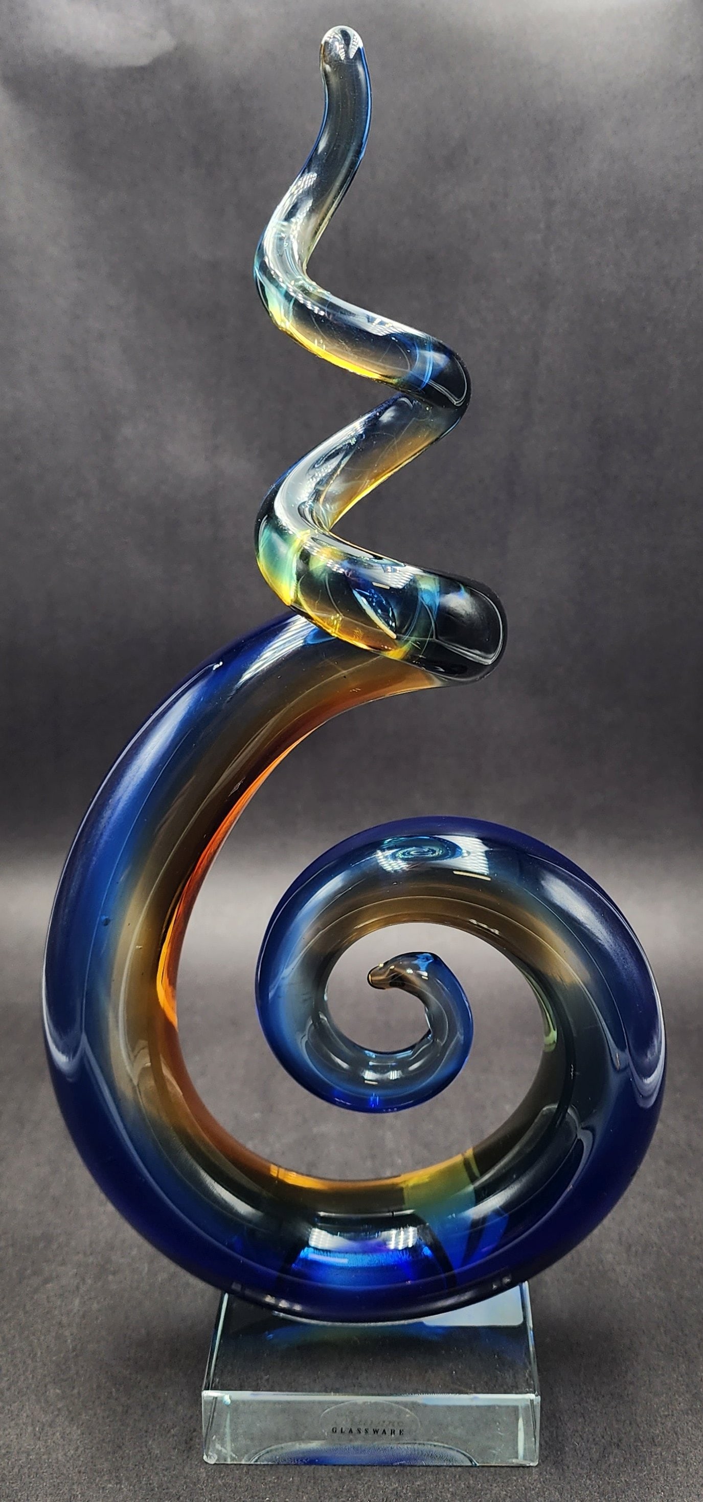 Colorful Vintage Spiral Art Glass Sculpture on Glass Base: Stunning piece in very good vintage condition; no chips, cracks, or repairs to the sculpture. Small chip to the transparent glass base. With original sticker. Measures approx. 12" tall x 5 3/4" wide x