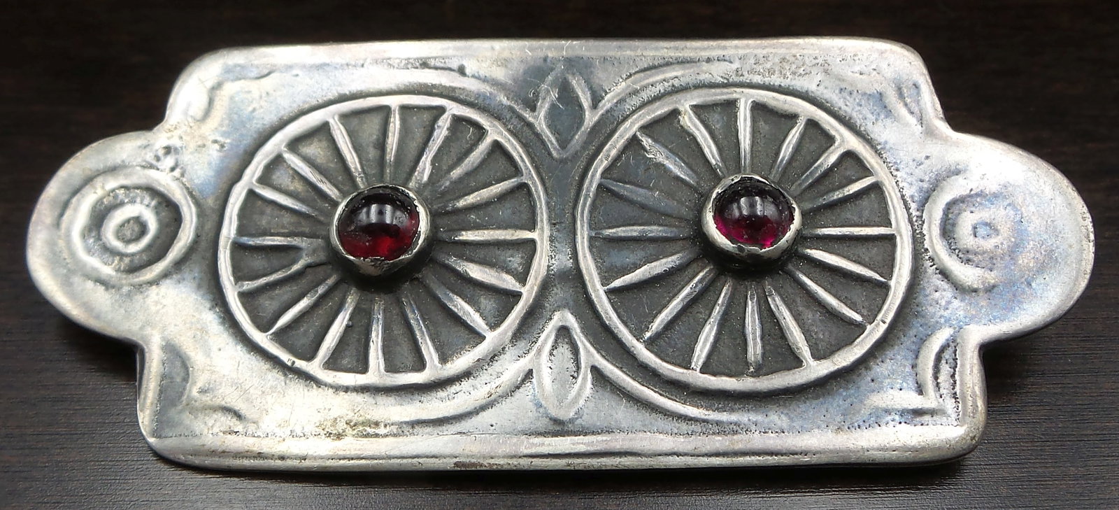 Very Unusual Mid-Century Modern Sterling Silver & Red Garnet Brooch: A very unusual piece featuring a wheel & spoke design adorned with deep red Garnet cabochons. Very good vintage condition with patina according to age. Measures approx. 2 1/2" wide x 1 1/16" high and 