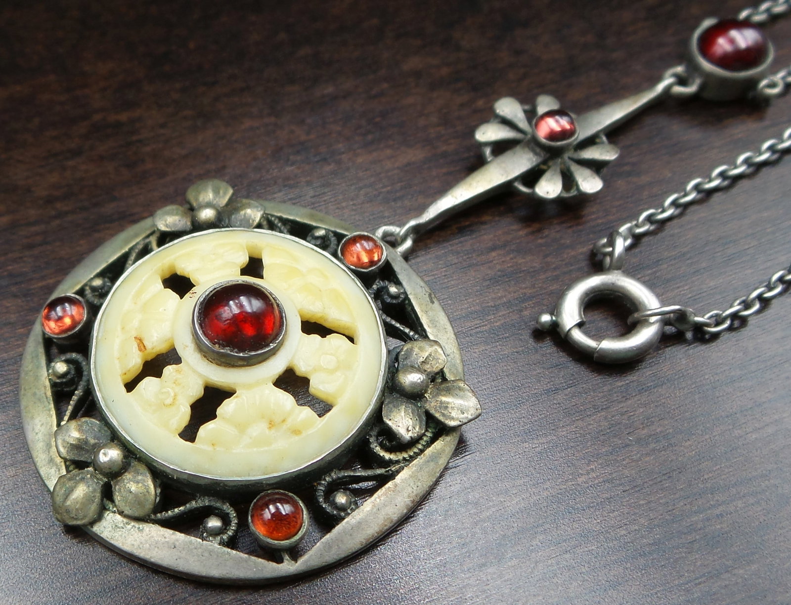 Rare Antique Art Nouveau Austrian 900 Silver, Bone & Garnet Pendant Necklace: This beautiful piece was made in Austria around 1900 and features an ornate floral frame set with a carved bone interior and adorned with several deep red Garnet cabochons. The pendant measures approx