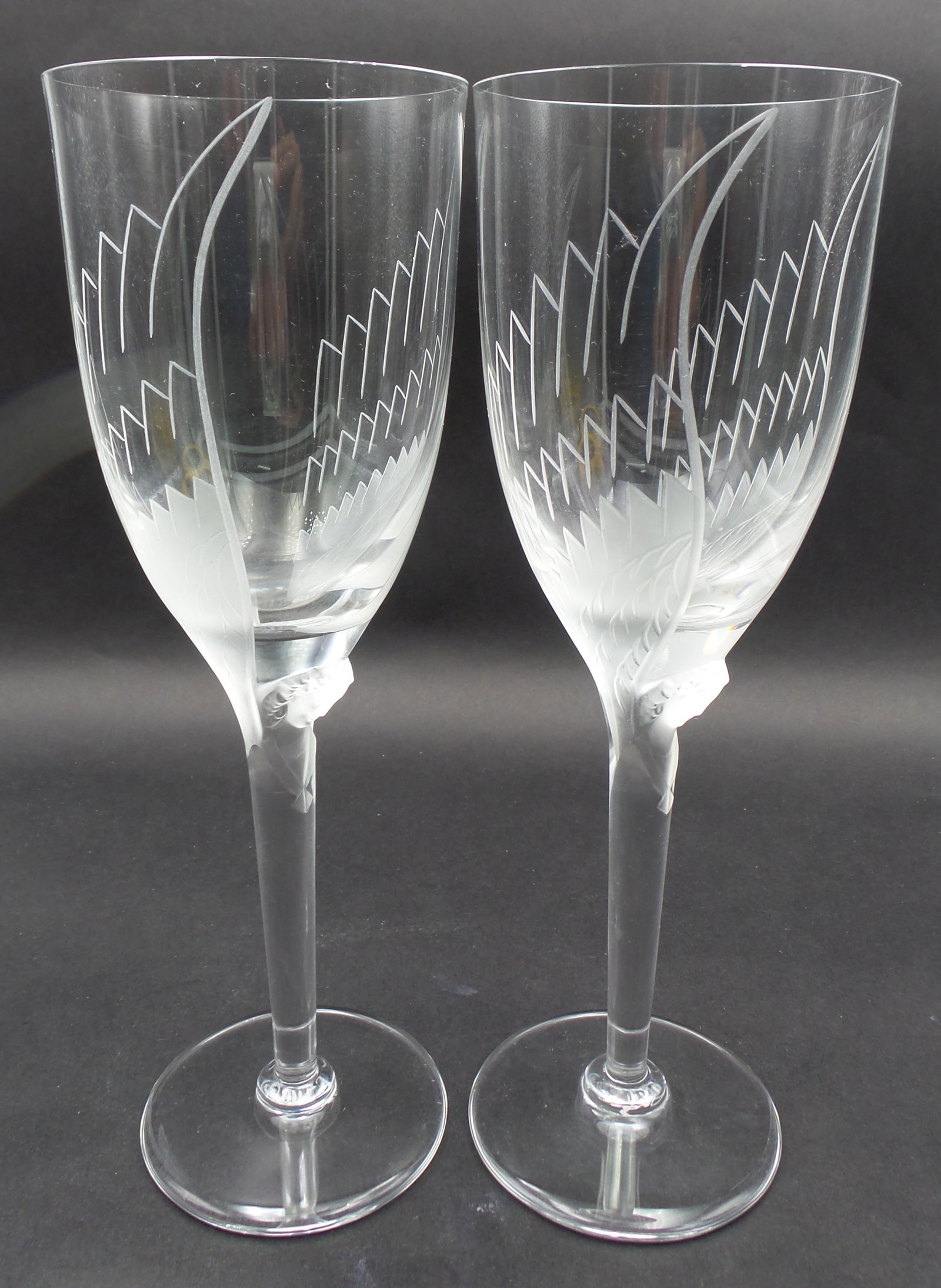 Pair of MARC LALIQUE (French 1900-1977) Frosted & Engraved Crystal Angel Champagne Glasses: MARC LALIQUE (French 1900-1977) PAIR OF FROSTED AND ENGRAVED CRYSTAL CHAMPAGNE FLUTES IN THE "ANGEL (ANGE)" PATTERN, WINGEN-SUR-MODER, DESIGNED 1948. Clear crystal flutes with cast and frosted angel h