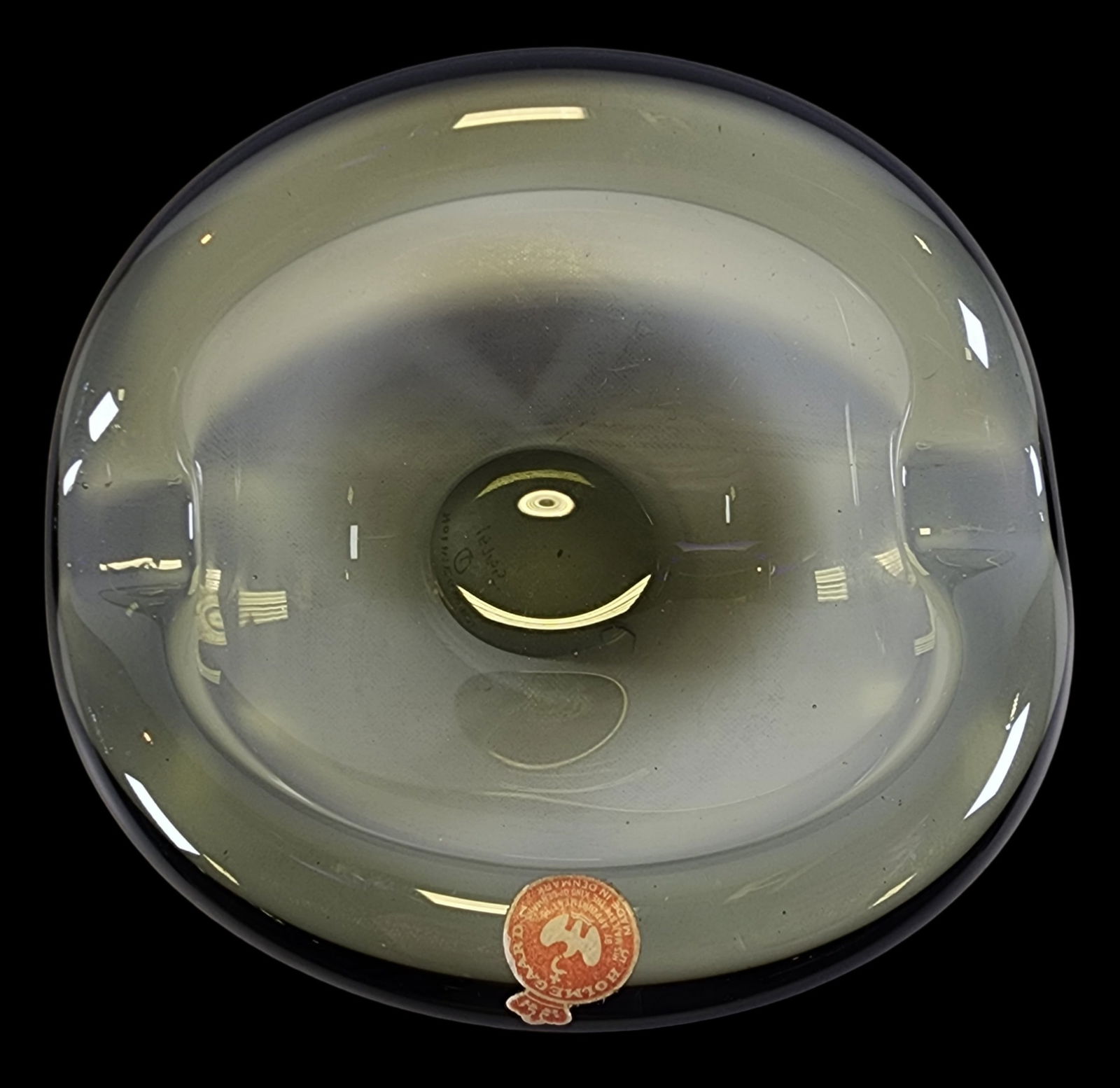 Small Mid-Century Modern Holmegaard Denmark Smoked Glass Curved Bowl: A mid-century smoked glass curved bowl by Holmegaard of Denmark. A flat base and circular form features curved wave-like rounded edges. Handblown in smoked grey glass with variances in color. Signed w