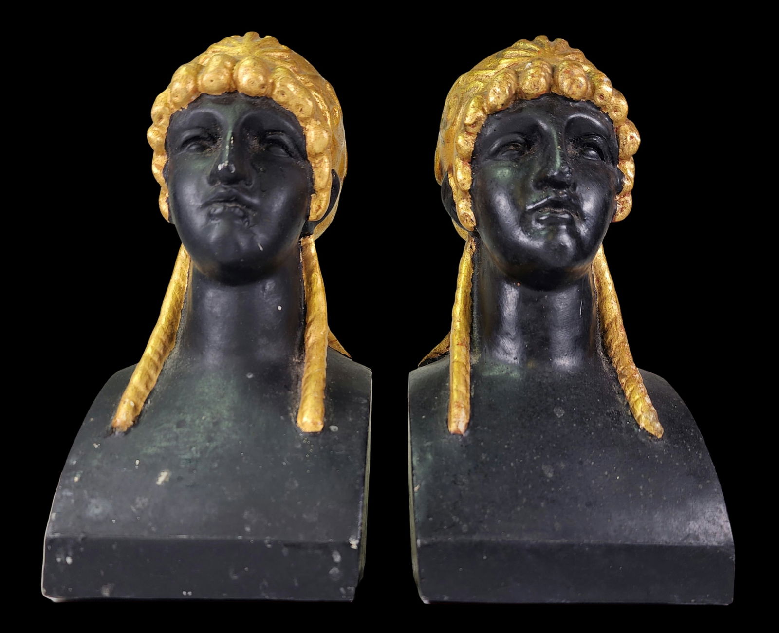 Pair of Art Deco Empire Style Busts of Greco Roman Women in Gilt and Black Plaster, Italy, ca. 1930: A stunning pair of 1930s plaster bookends/busts of Greco-Roman women with ornate headdress hand painted in 24K gold leaf. The busts feature integral plinth bases and have been hand-painted in black. T