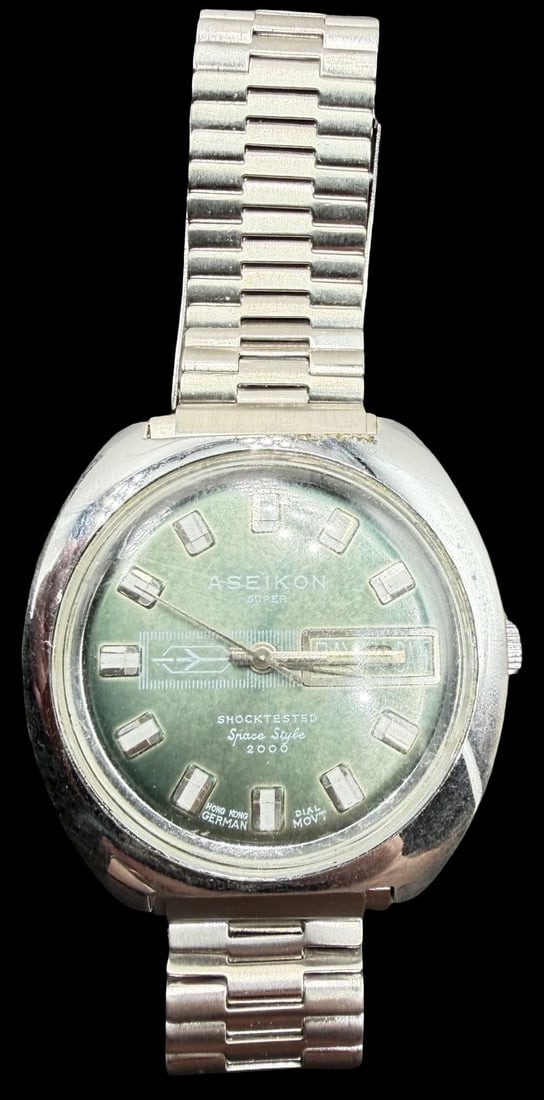 Vintage ASEIKON Stainless Steel Gold Tone & Green Dial Watch: Very good vintage condition with minor patina according to age. Dial measures approx. 1" long and 1" wide and weighs ca. 70.01 grams. Marked for ASEIKON. The timepiece is currently not working.