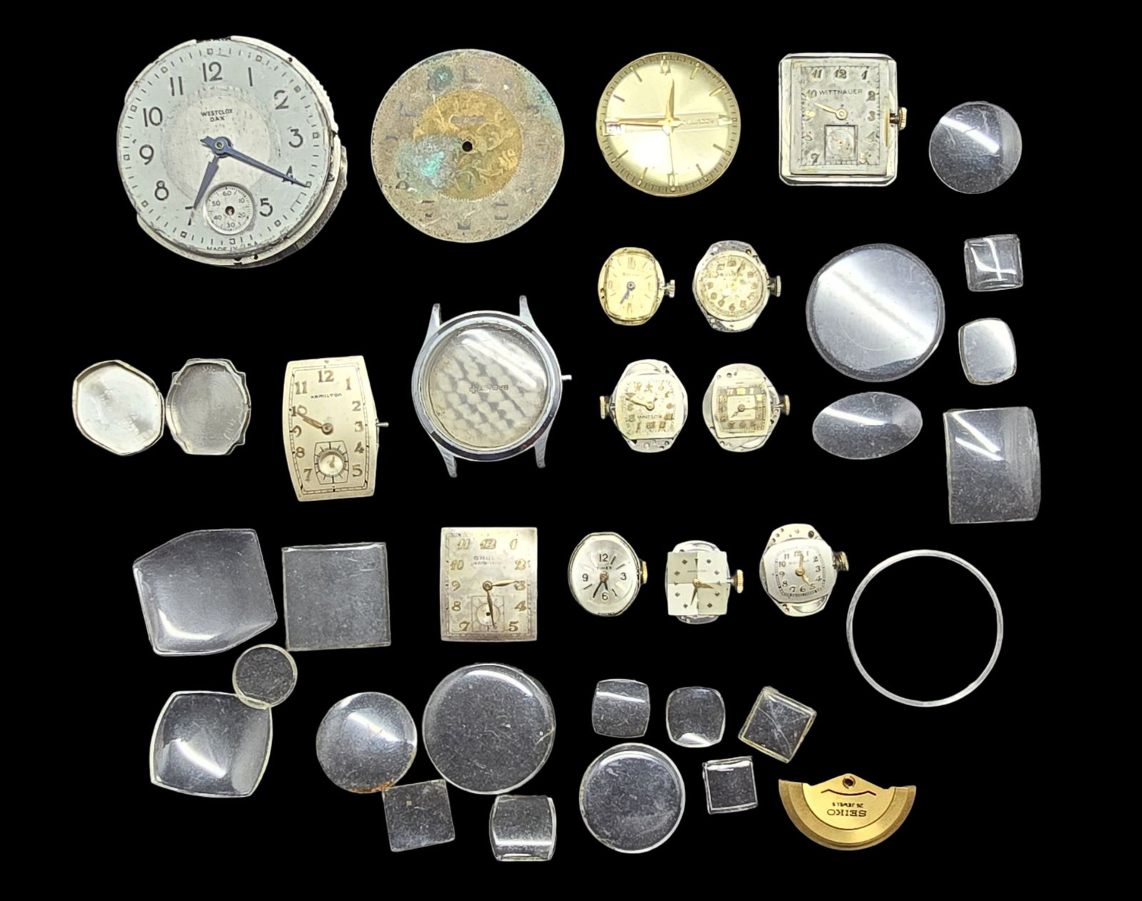 Lot of Watch Movements & Watch Parts: Very good vintage condition w/ wear and patina according to age; missing hand for one movement. The largest piece measures approx. 1 1/2" high and 1 1/2" wide.
