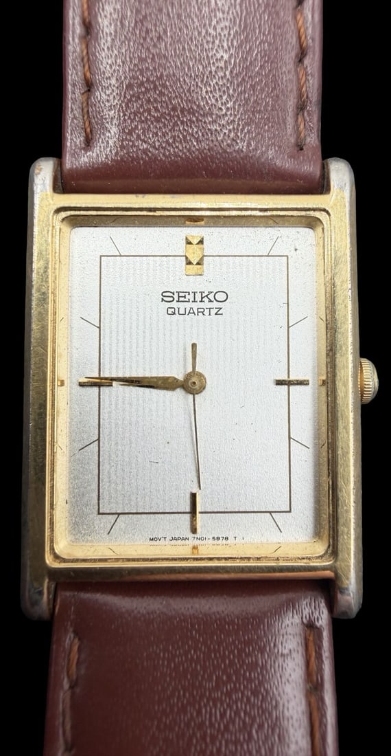 Vintage Mid-Century SEIKO Stainless Steel & Gold Tone w/ Brown Leather Strap Quartz Watch: Good vintage condition w/ minor patina according to age. Dial measures approx. 1" long and 3/4" wide. No Glass. Batteries need to be changed. Untested. Weighs ca. 21.44gm. Marked for SEIKO.