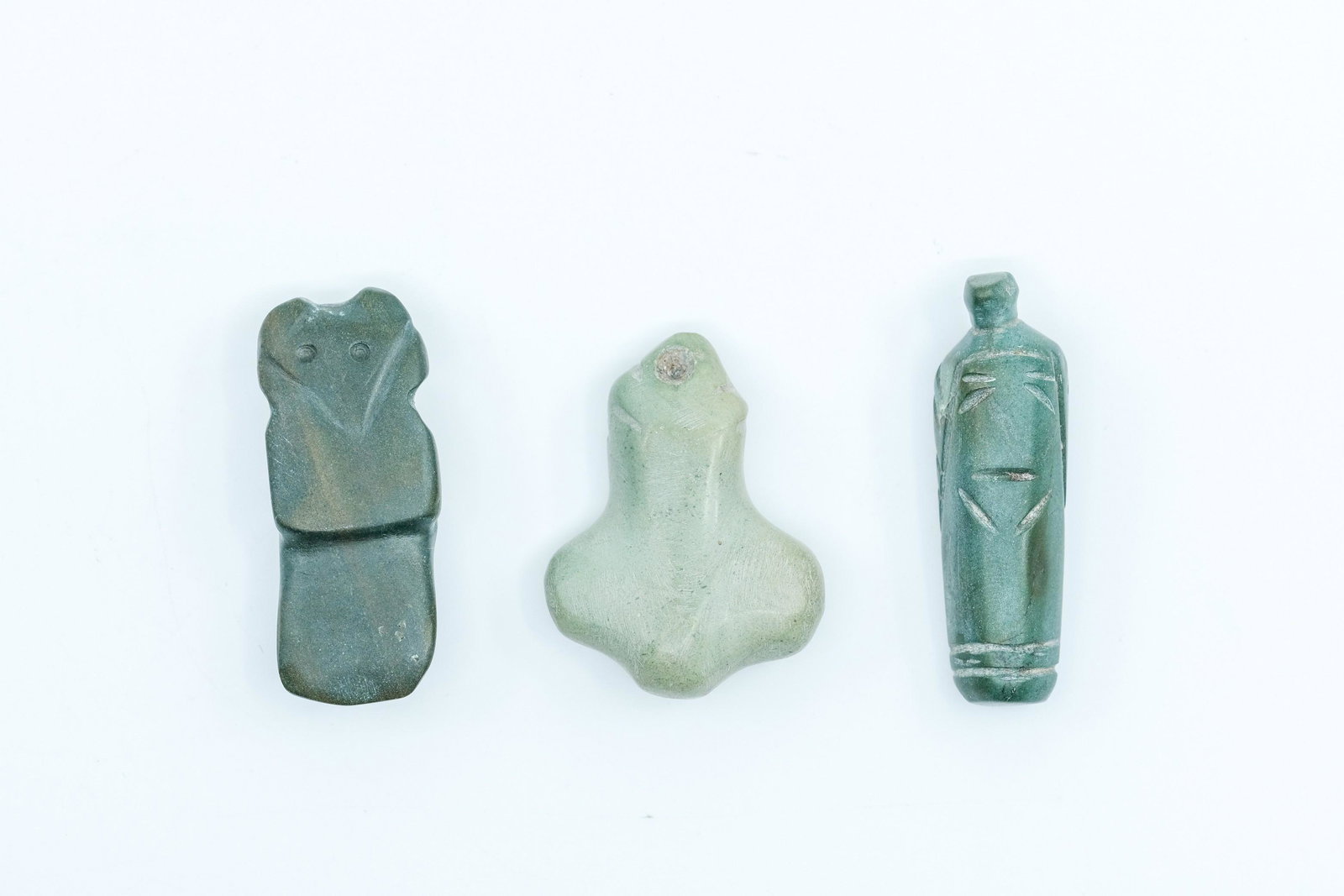 Pre-Columbian Carved Face and Pendants, Trio: Pre-Columbian Carved Face and Pendants, Trio, First is a Jade carved pendant, Hole drilled for suspension, Second is a green stone carved avian axe God pendant, avian features, Hard dark green stone, 