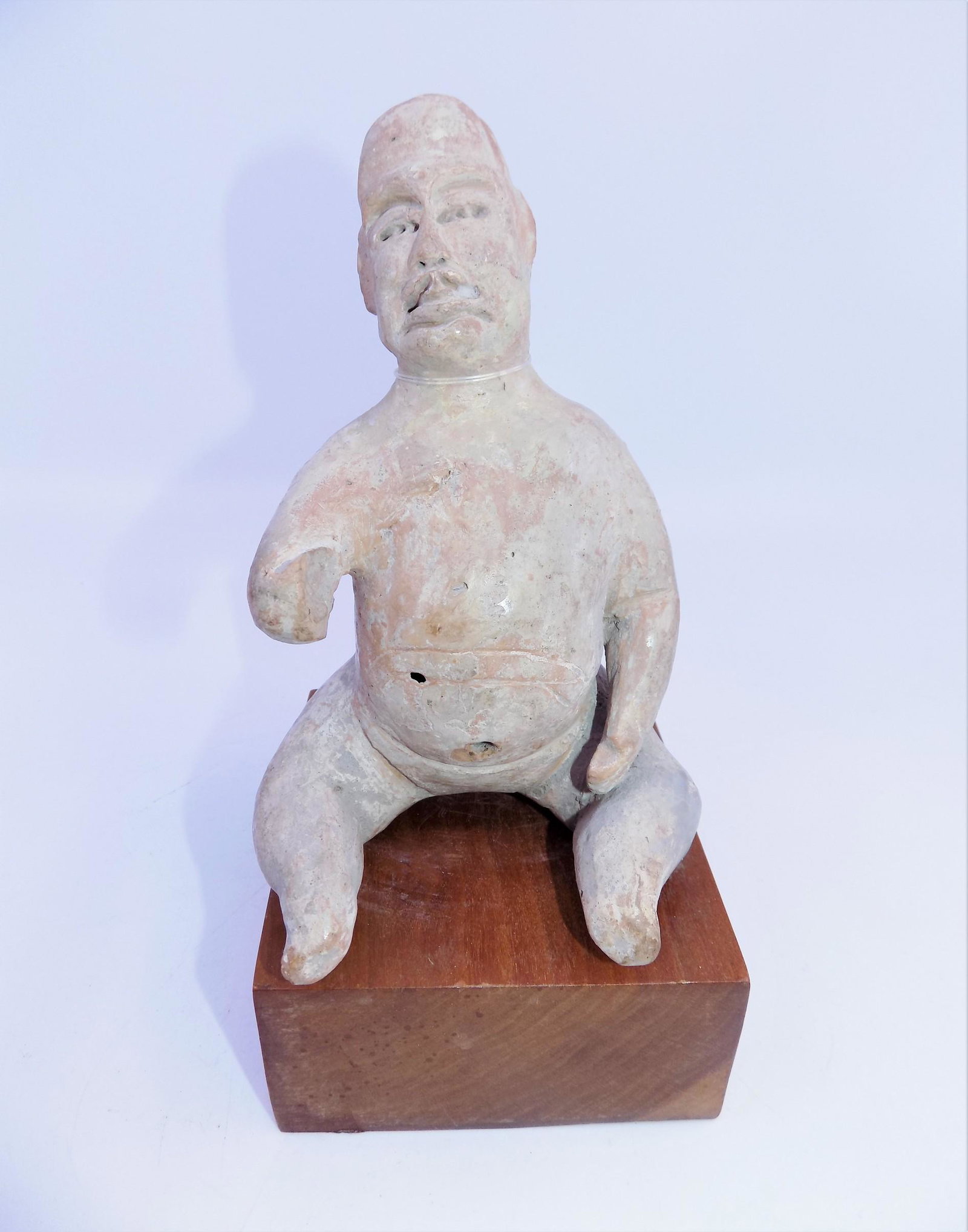 Pre-Columbian Olmec Carved Clay Figure: Pre-Columbian Olmec Carved Clay Figure, Sitting upright, Missing one hand, Stand Included. Measurements: Off Stand: 5 1/4" x 3 3/4" , Weight: 1 1.8 OZ.