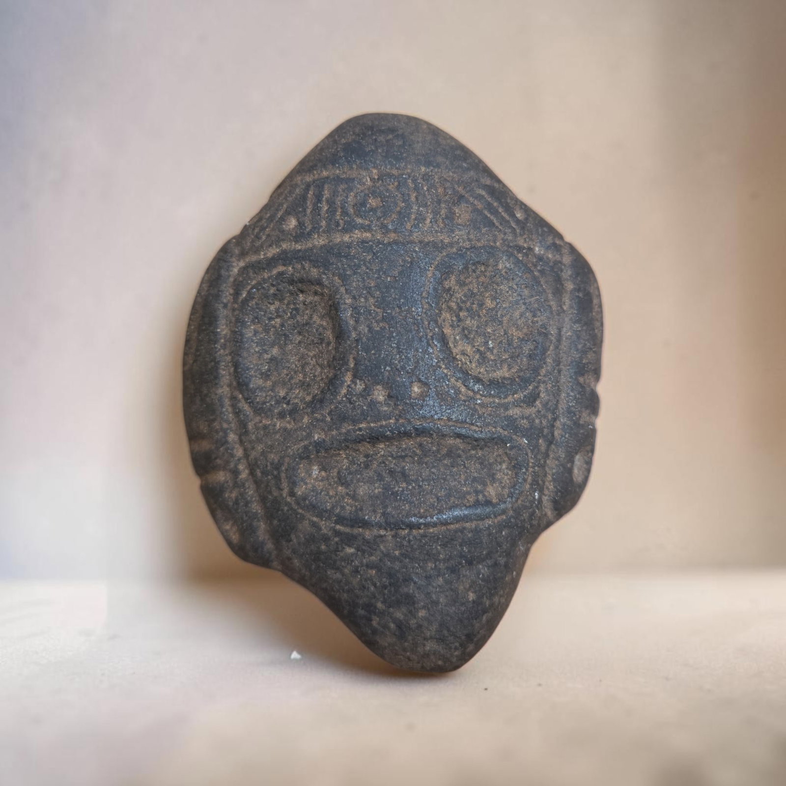 Pre-Columbian Taino Stylized Mask Zemi Stone Effigy: 4.5" x 5" Pre-Columbian Taino Ceremonial Zemi Stone Effigy, Geometric Incised Markings, Symmetrical Circular Depressions, Taino Culture, 800-1200 C.E.