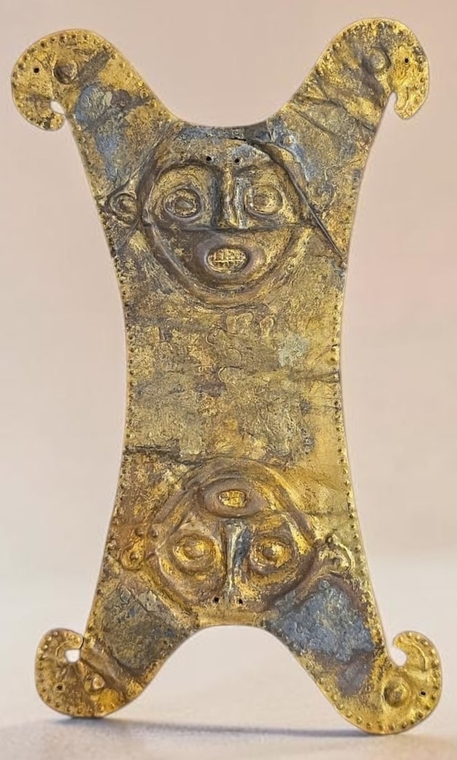Pre-Columbian Colima Gold-Tumbaga Pectoral Ornament: 11" x 6.25" Pre-Columbian Colima Gold-Tumbaga Pectoral Ornament, Hammered Gold Sheet metal repousse human deities stacked vertically flanked by curved wing corners. Worn as a chest piece of pectoral p