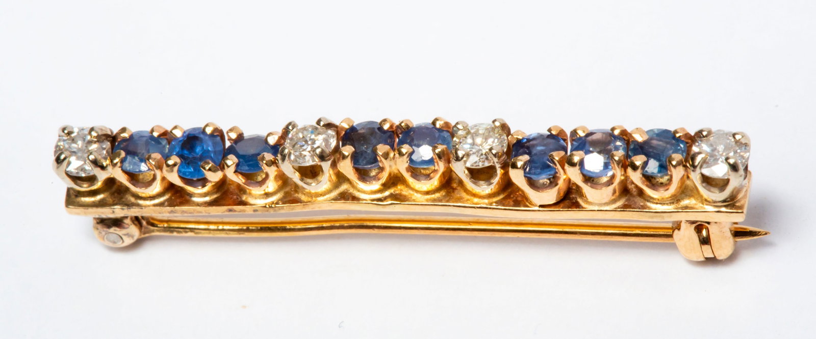 A Vintage 14K Gold Diamond and Spinel Bar Pin: Spectrometer tested 14k, four diamond set in white gold with blue spinel (possibly some sapphire) set between them in yellow gold, the stones range around 2.7 mm to 3 mm, the brooch has irregular line