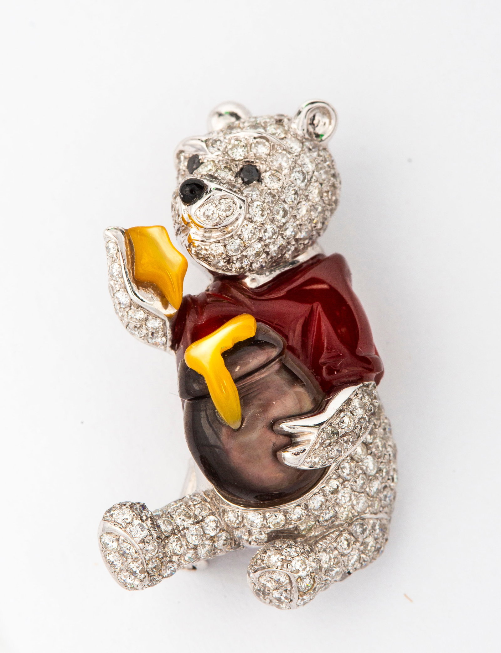 An Estate 18K Gold and Diamond Winnie the Pooh Brooch Pendant: Marked on the back, "18K 750", "670 D002135", white gold Winnie the Pooh form covered in pave set diamonds and accented with mother of pearl for the shirt, honey and honey pot, black diamond eyes, the