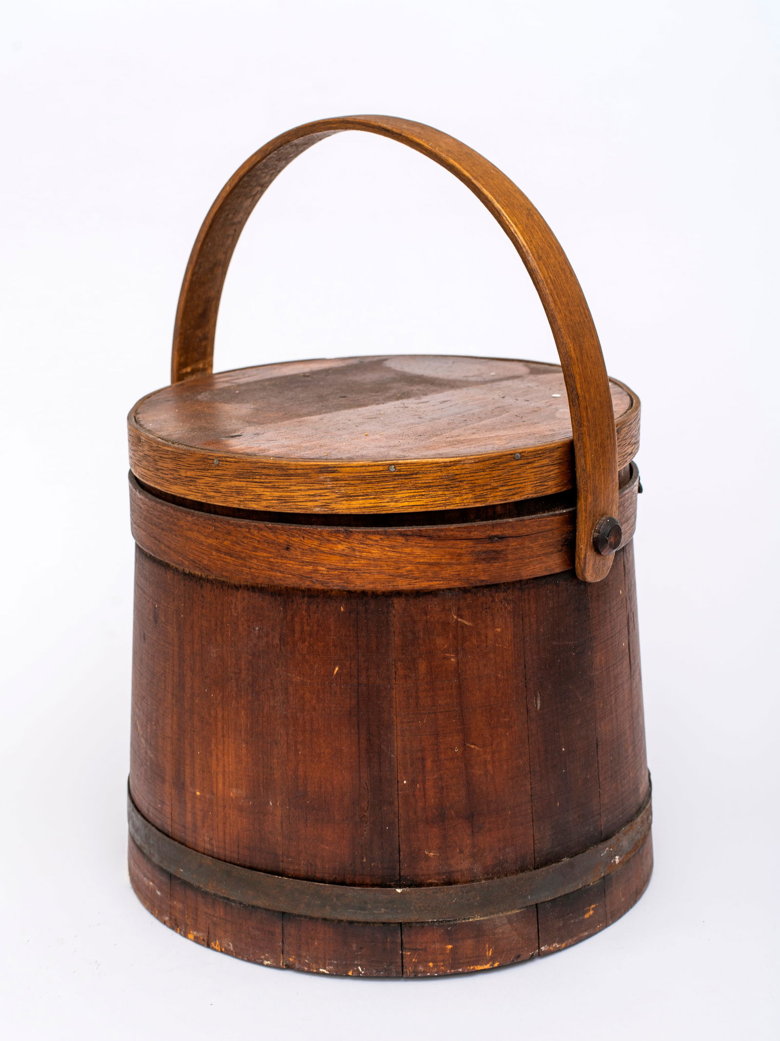An Antique Firkin: Unmarked, with pine and iron hoops, wood handle attached with dowels, some surface wear and old paint dots, 9 7/8" tall excluding handle, 10" lid diameter. 