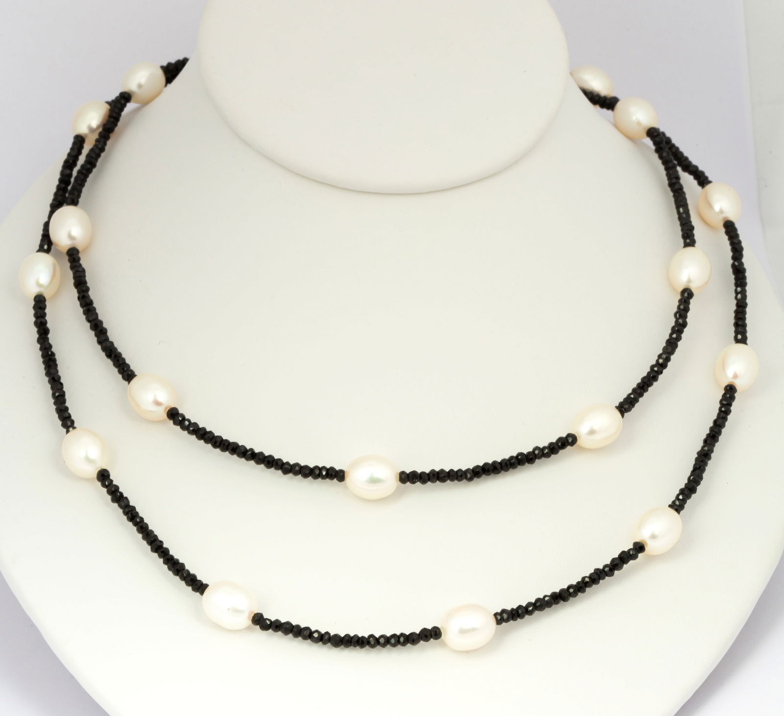 A Black Spinel and Pearl Necklace with 14K White Gold Clasp: Marked 14k on clasp, 36 1/2" length, oblong white pearls stationed on a strand of faceted black spinel rondelle beads, 18 pearls in total, a total weight of 33.5 grams. 