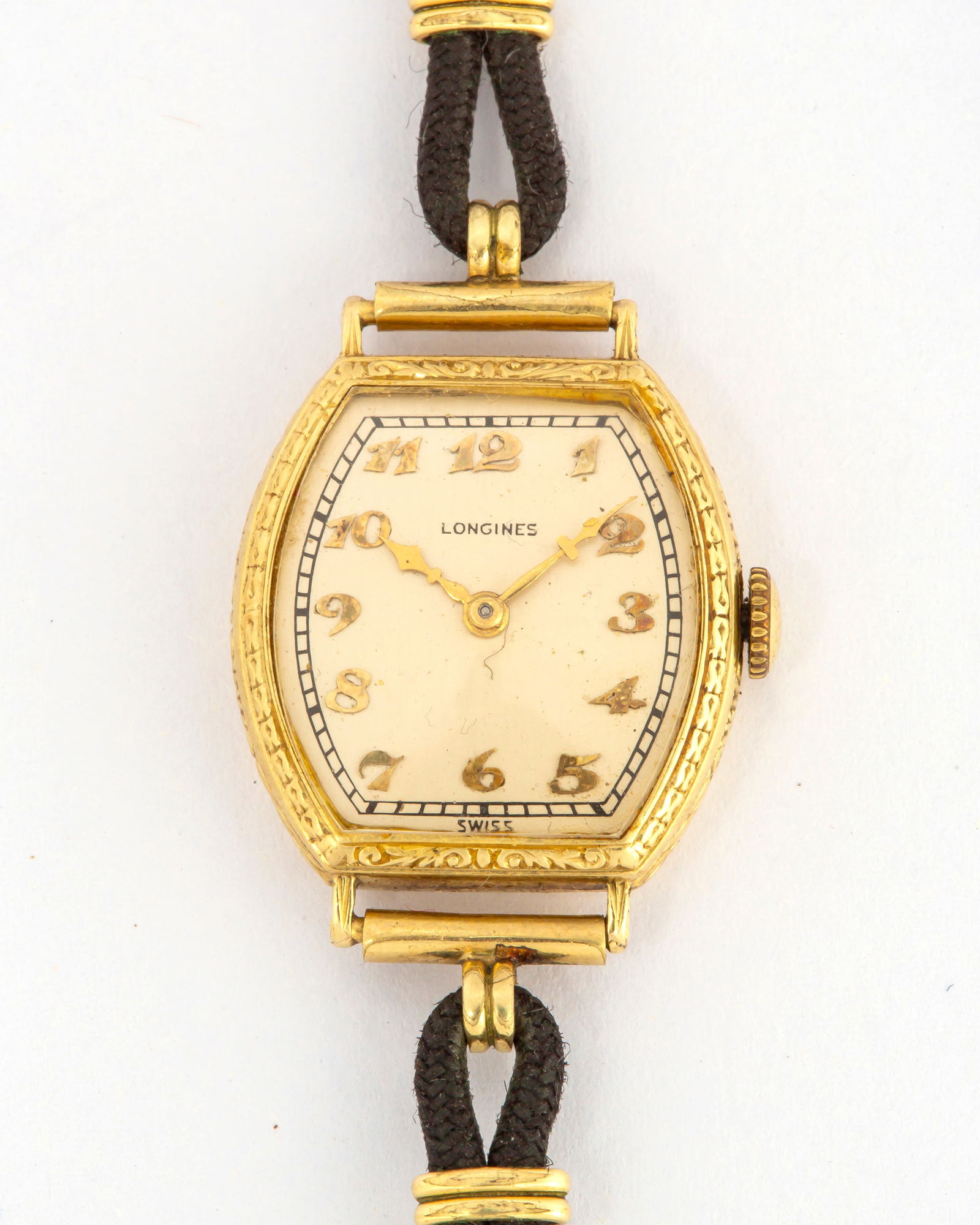 An Antique Ladies 14K Gold Longines Wrist Watch: Marked on the inner back case, "14K, AW, 3735068, Longines W.Co, Swiss", 15 jewels, gold numerals on silvertone face, engraved case with monogramed back of case, "NM", on a bl