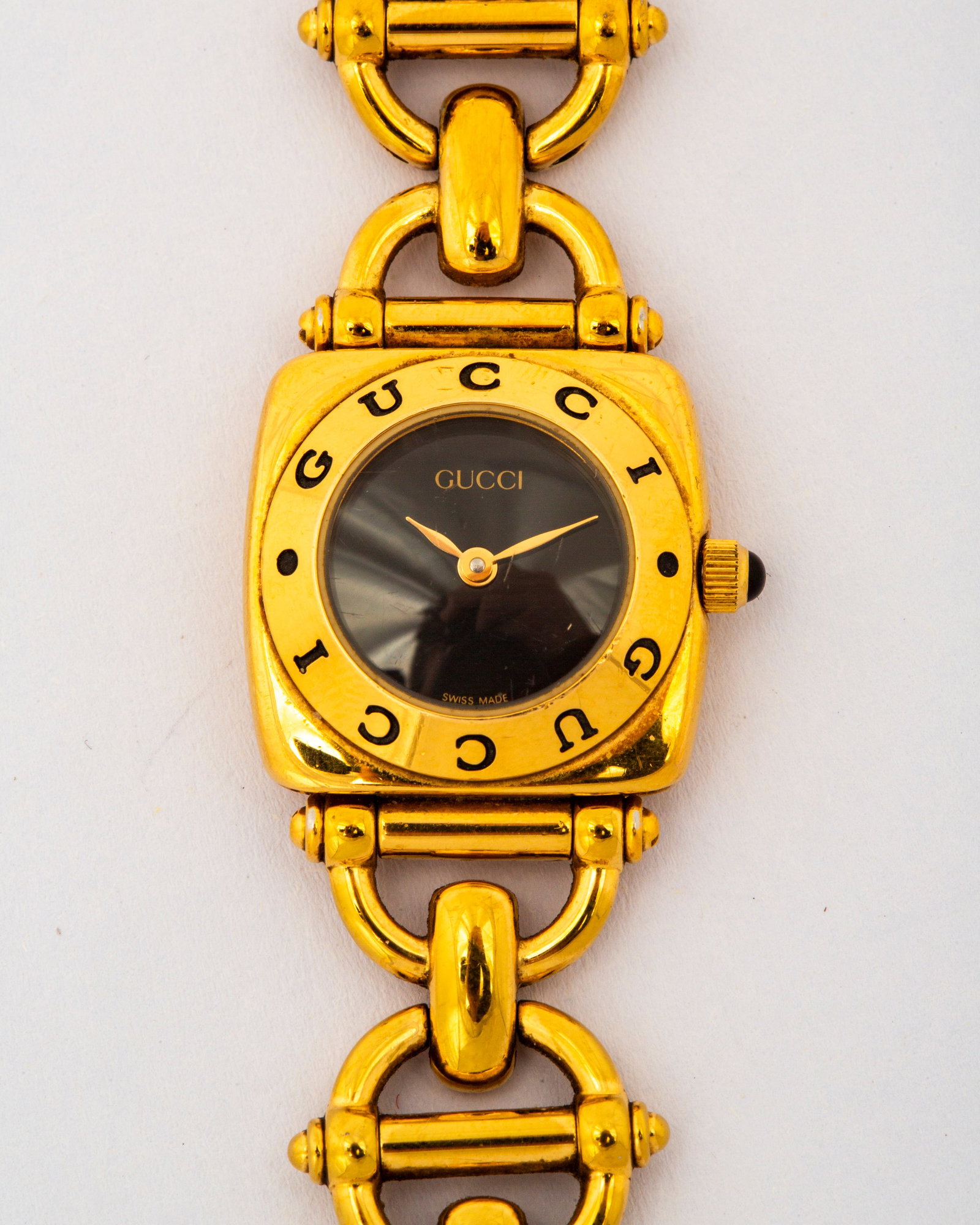 A Gold Plated Horsebit Gucci 6400L Watch: Marked on the black dial, the bezel, the clasp and the back, horsebit construction band, back with Gucci insignia, stainless steel, water resistant, Swiss made, 6400L, 0078915, 7 1/4" in len