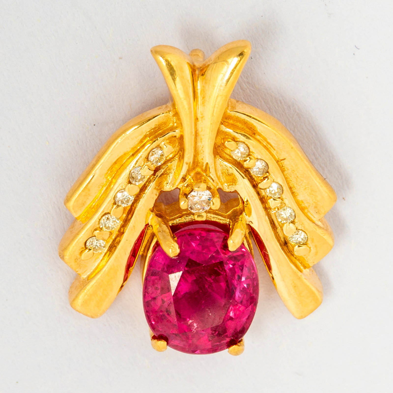 An Estate Gold, Pink Sapphire and Diamond Pendant: Marked, "ALA" with copyright, an oval pink sapphire roughly 9mm x 7mm set in four prongs (slightly askew and loose, could be adjusted by jeweler), with flowing gold sides and diamond accents