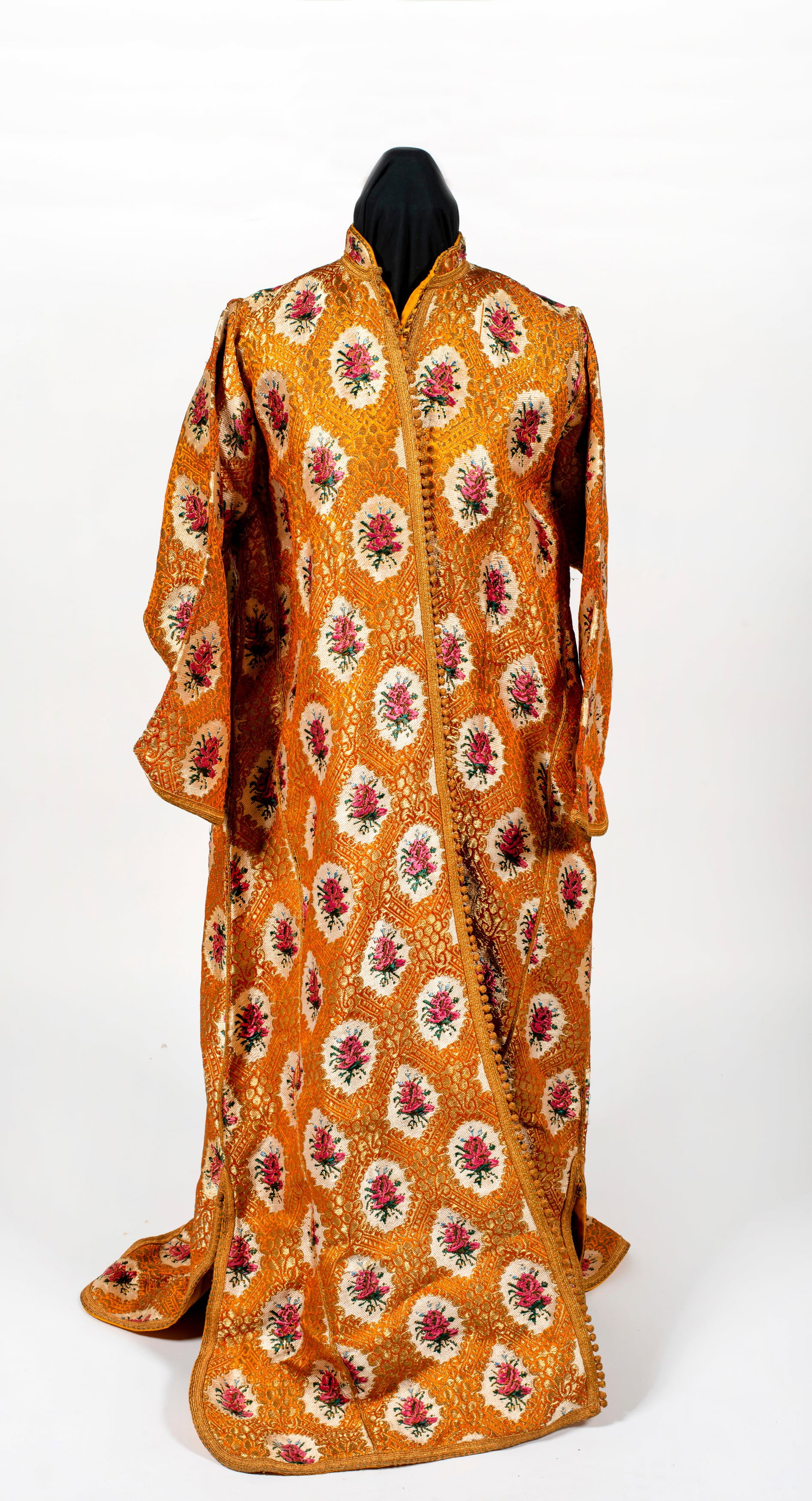 A Brocaded Silk Moroccan Kaftan, Qaftan Khrib Fasi: Open down the front with small ball buttons (iqad); round collar, vibrant pink flowers on white lozenges over a mustard gold ground; normal signs of wear from use and age; slight musty smell. &nb