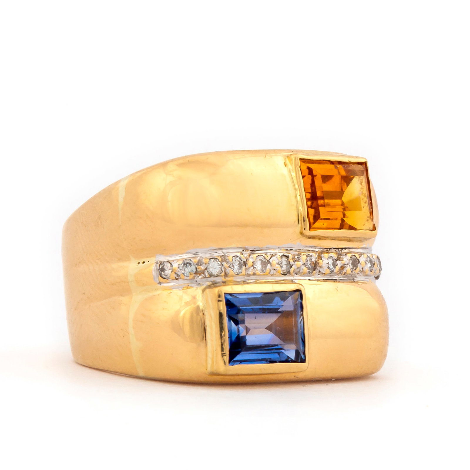 Ming's 18K Gold Sapphire and Diamond Ring: Marked "18K, 750, Ming's" 15.4 mm wide band with two off set step cut bezel set stones, a blue sapphire and yellow gemstone set east to west with center row of diamonds, the yellow stone shows some mo