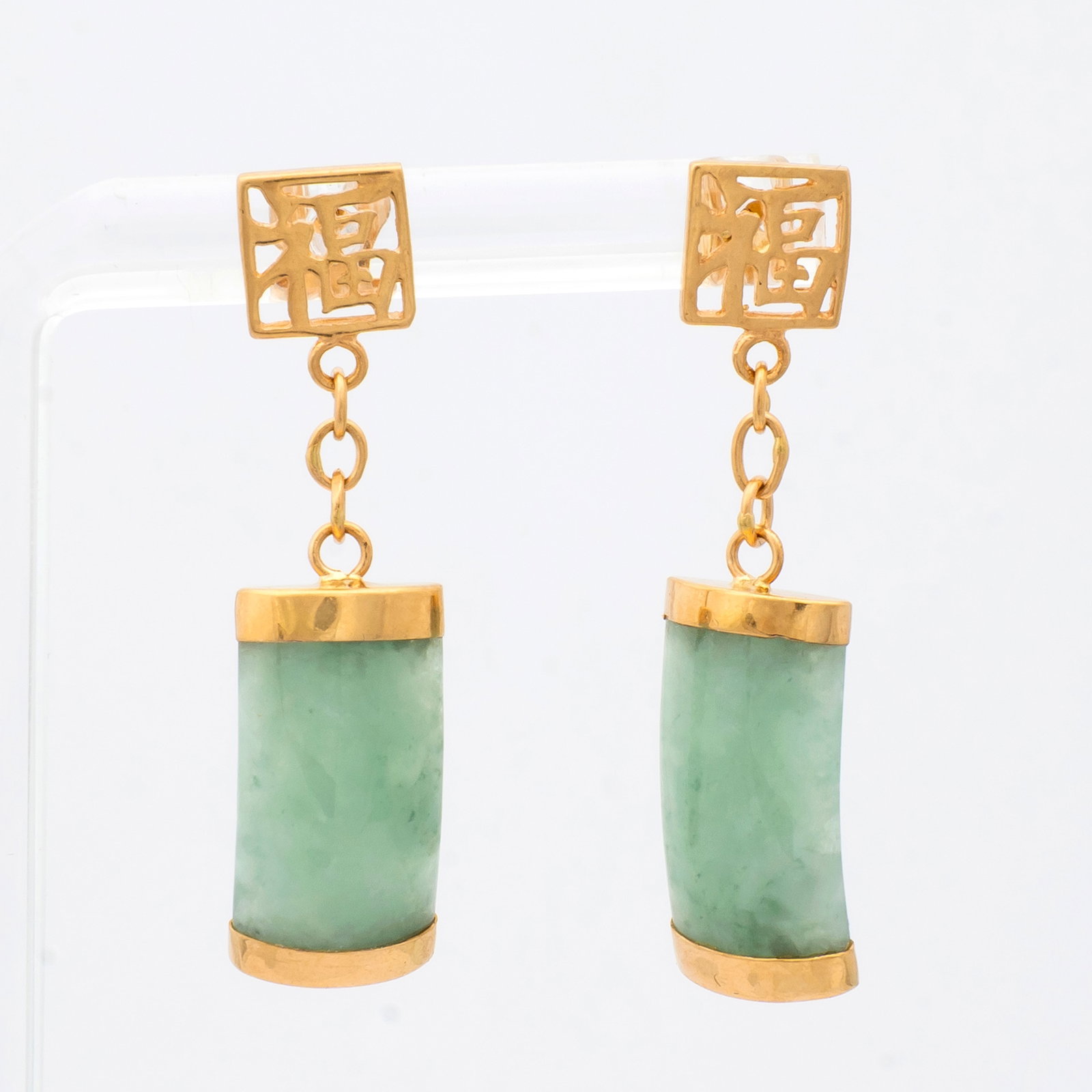 A Pair of 14K Gold Character and Jade Drop Earrings: Marked on the bottom and the earring posts, "14K", the post with square pierced character mark with a 5/16" wide slightly domed piece of green and white jade, a total drop of 1 1/2" and a total