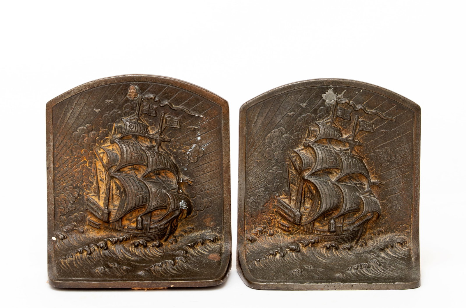 Bron Met Ship Cast Iron Bookends: Marked, "Bron Met" along with indecipherable numbers, each depicting a ship on a rocky sea, an additional insignia added to one and missing from the other with remnant of solder, each 5 1/2" tall,