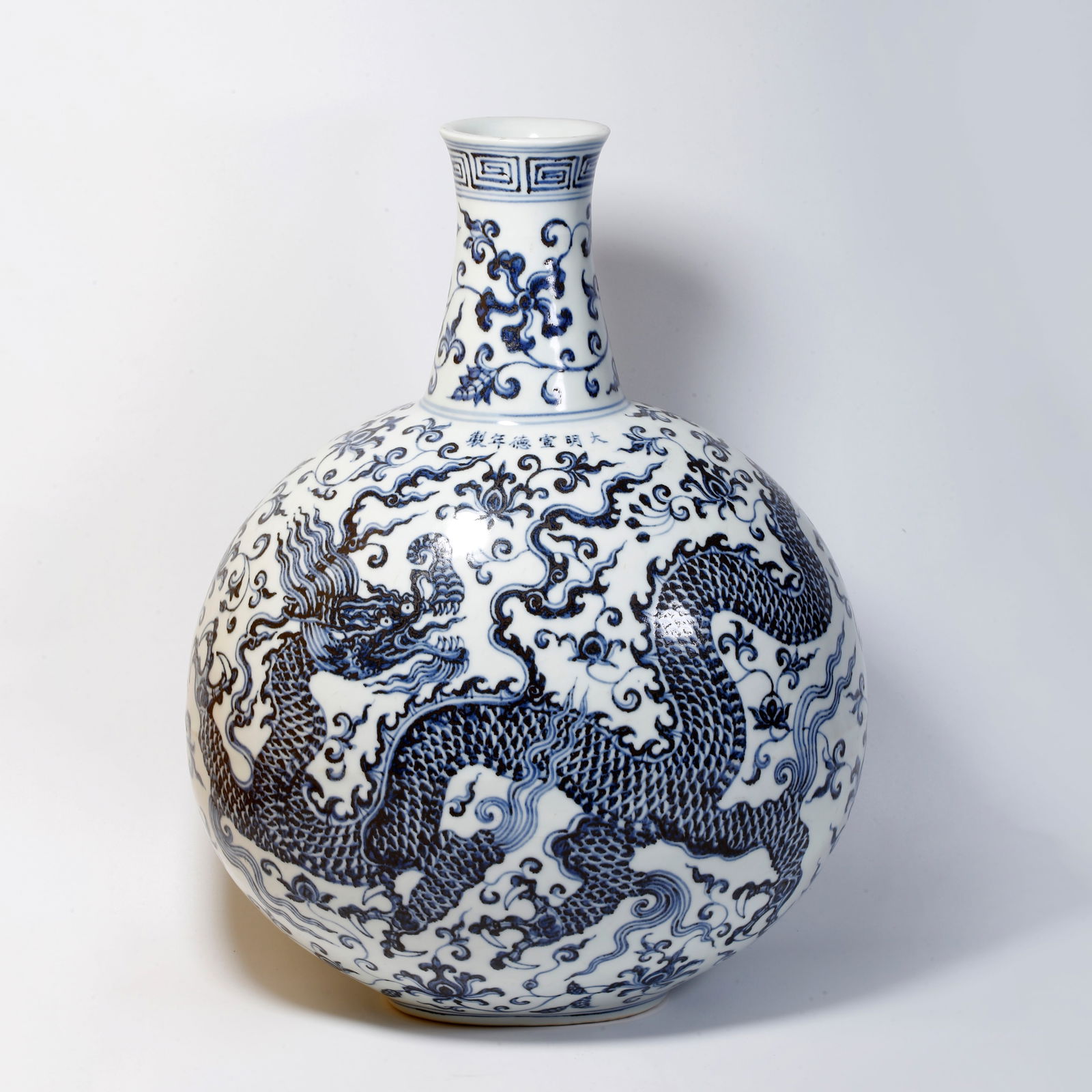A BLUE AND WHITE FLORAL DRAGON PATTERNED MOON-SHAPED BOTTLE: Blue and white floral dragon patterned moon-shaped bottle