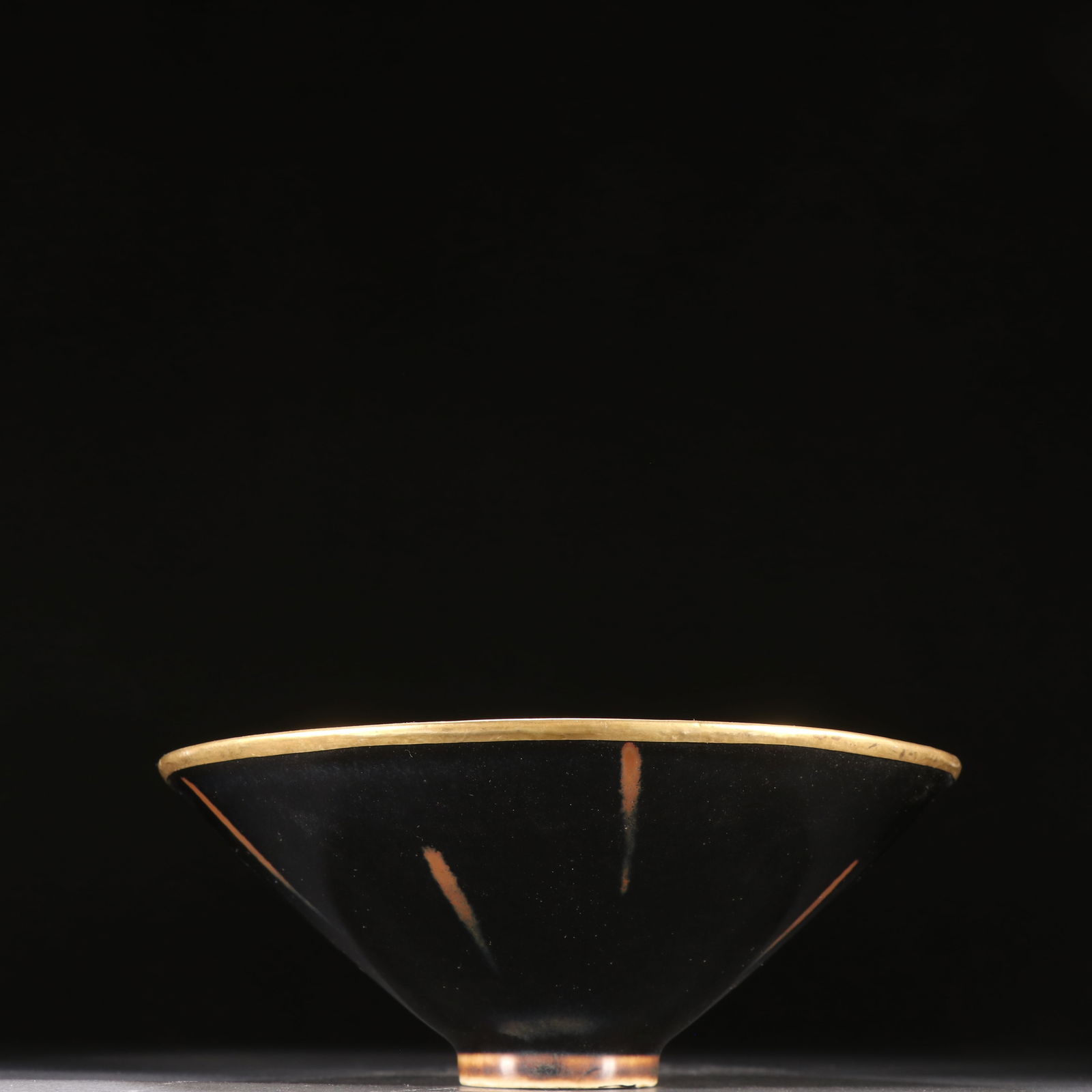 A BLACK-GLAZED GOLD-MOUNTED TEA CUP: Black-glazed gold-mounted tea cup