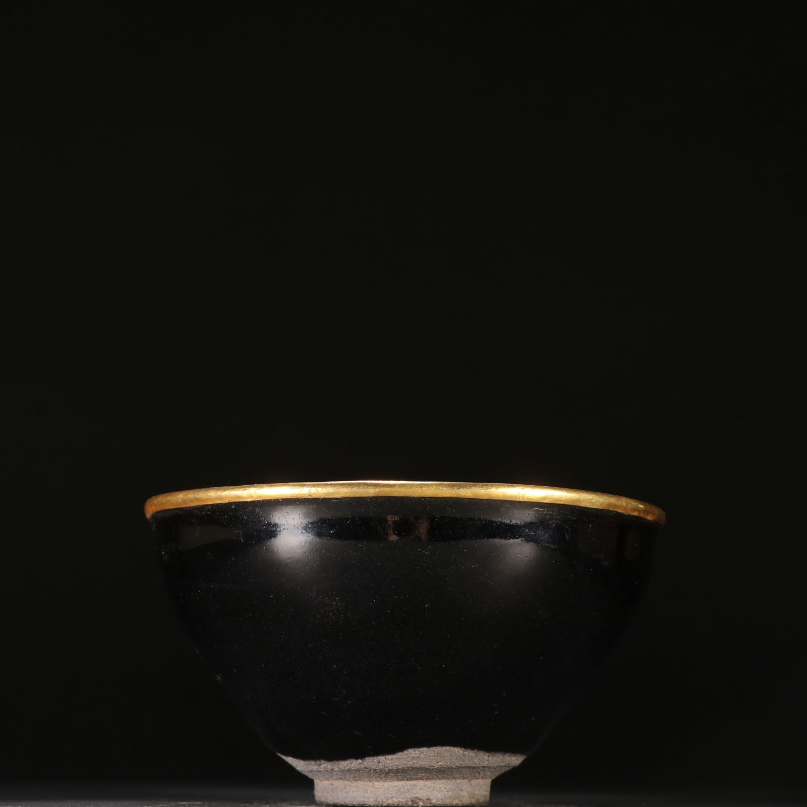 A BLACK-GLAZED GOLD-MOUNTED TEA CUP: Black-glazed gold-mounted tea cup