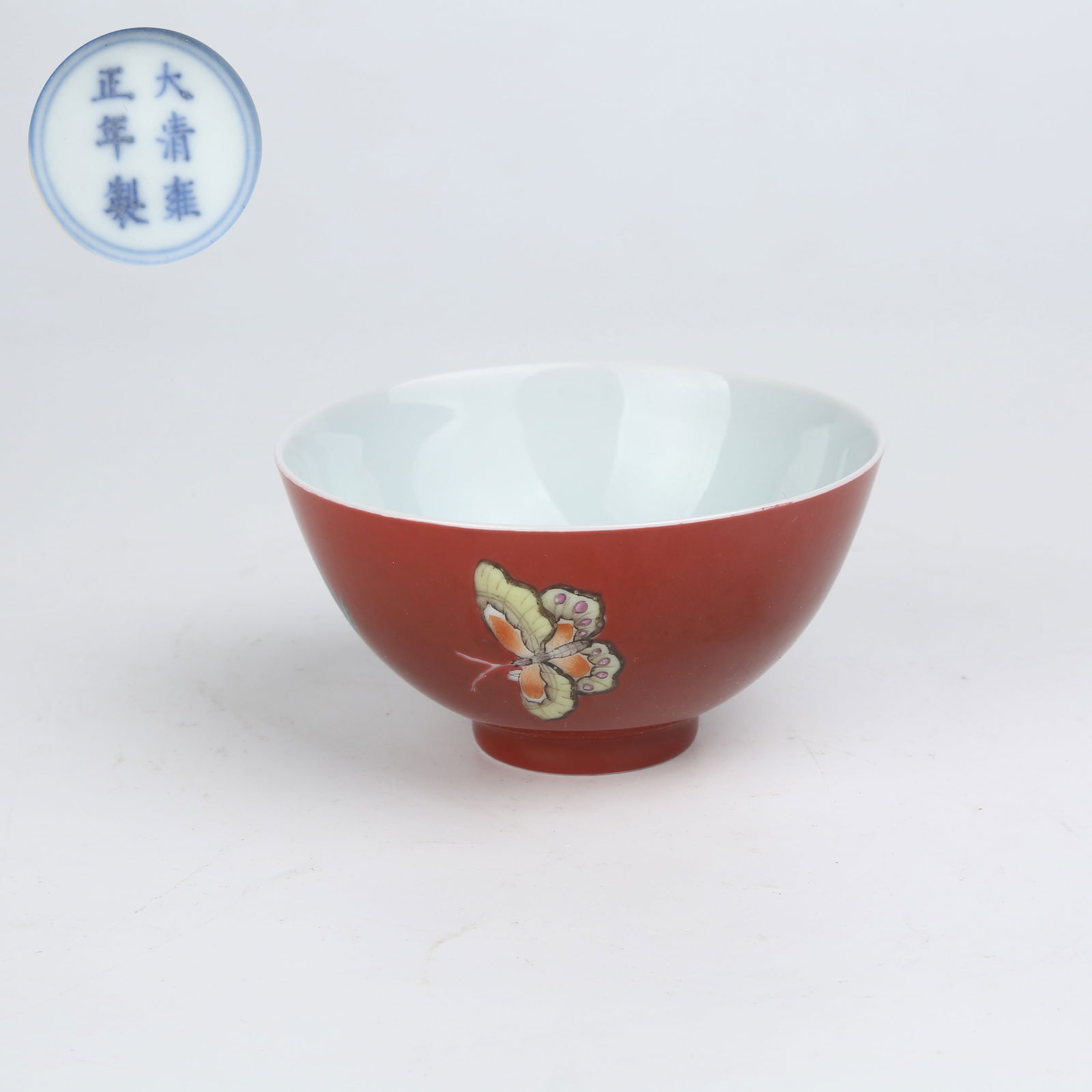 A RED-GROUND FAMILLE ROSE CUP WITH FLORAL AND BUTTERFLY PATTERN: Red-ground famille rose cup with floral and butterfly pattern