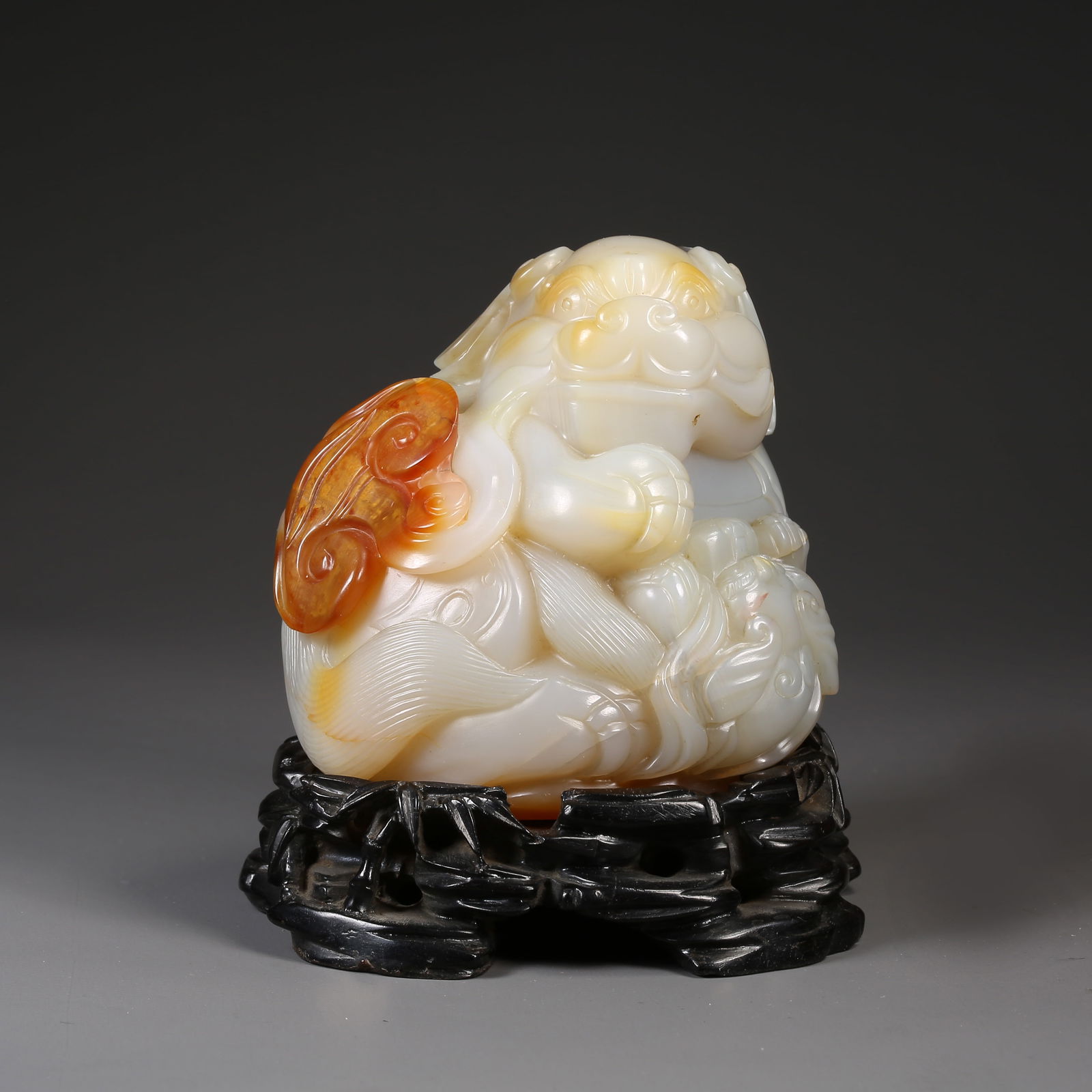 A AGATE CARVING OF A LION PLAYING WITH A BROCADE BALL ORNAMENT: Agate carving of a lion playing with a brocade ball ornament